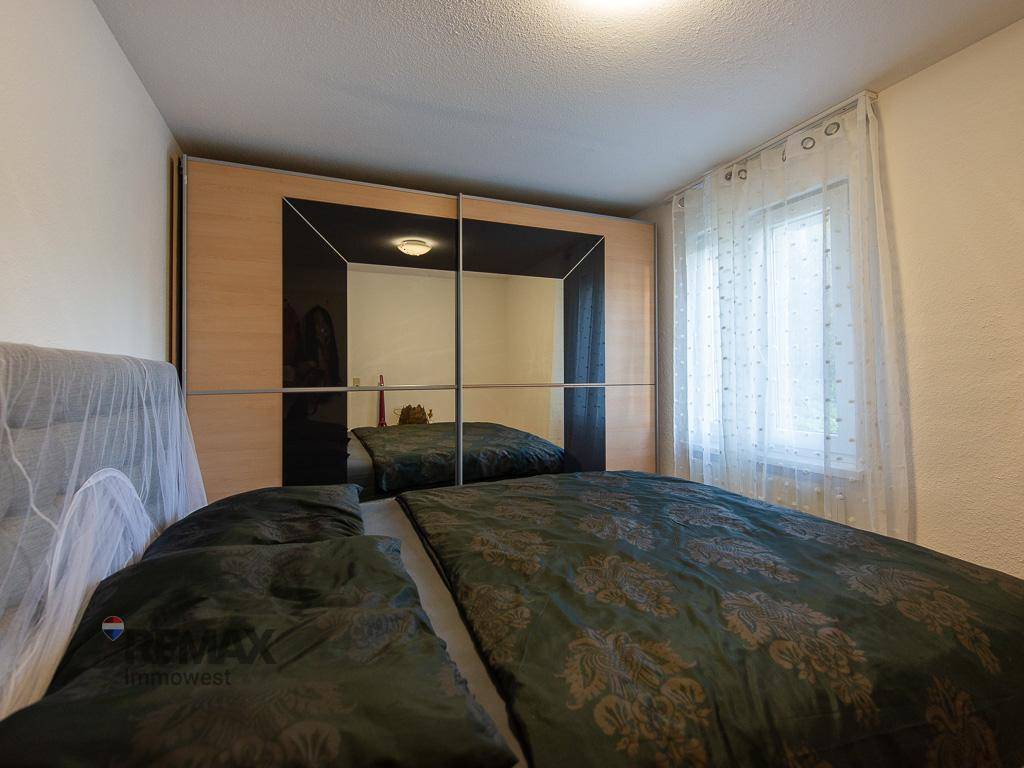 Schlafzimmer mit Doppelbett, Spiegelschiebetüren und Holzboden.