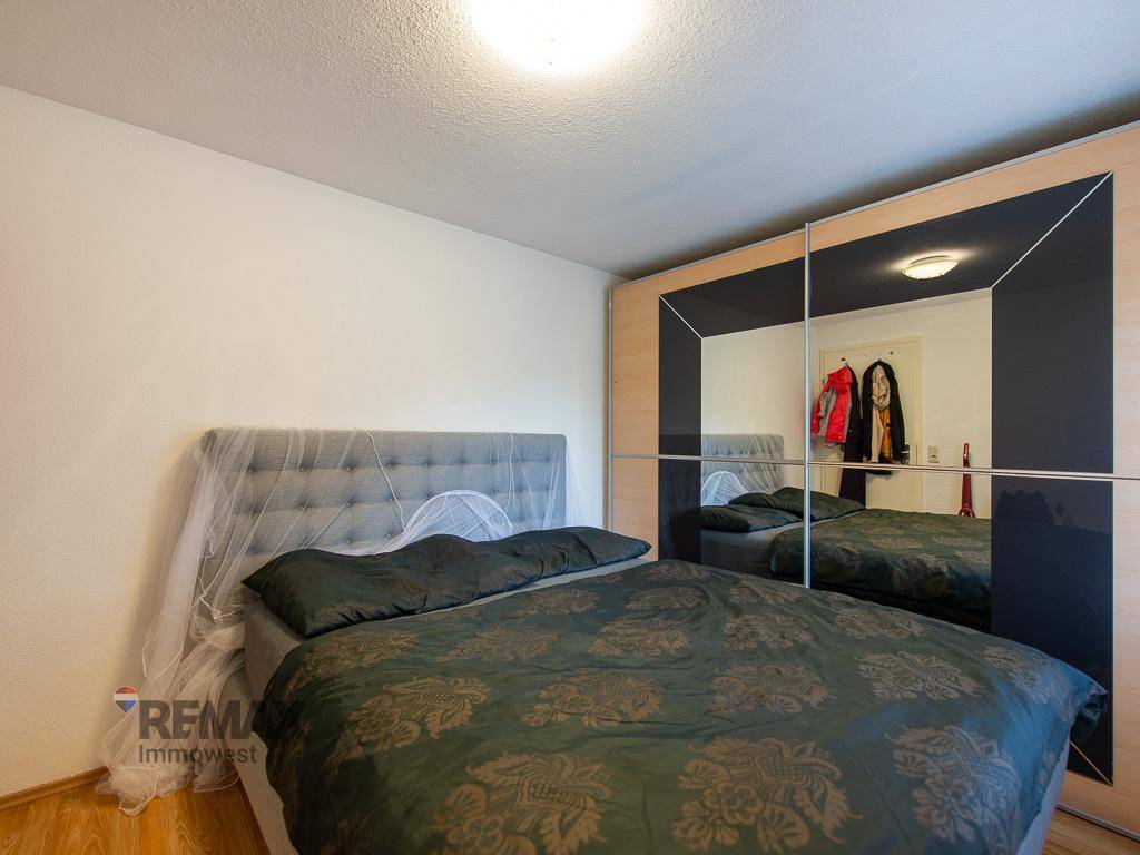 Helles Schlafzimmer mit Doppelbett, Spiegelschiebetüren und Holzboden.