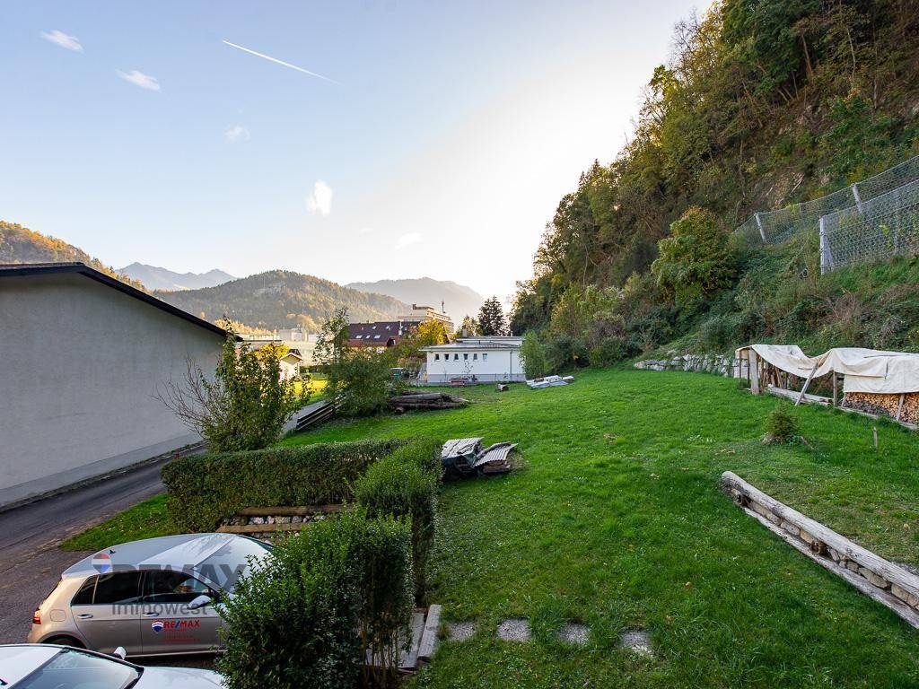 Weitläufiger Garten mit Rasenfläche und Panoramablick auf die Berge und die Umgebung.