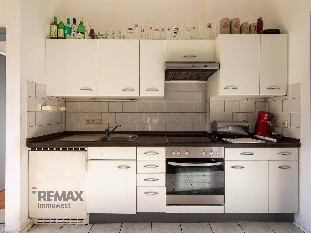 Kompakte Küchenzeile mit weißen Schränken, Backofen und Spüle, ideal für effizientes Kochen.