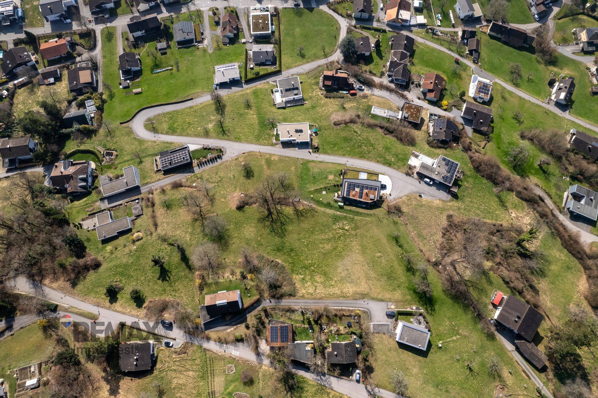 Ausgedehnte Luftaufnahme einer Wohngegend mit vielen Häusern, grünen Hügeln und Straßen.