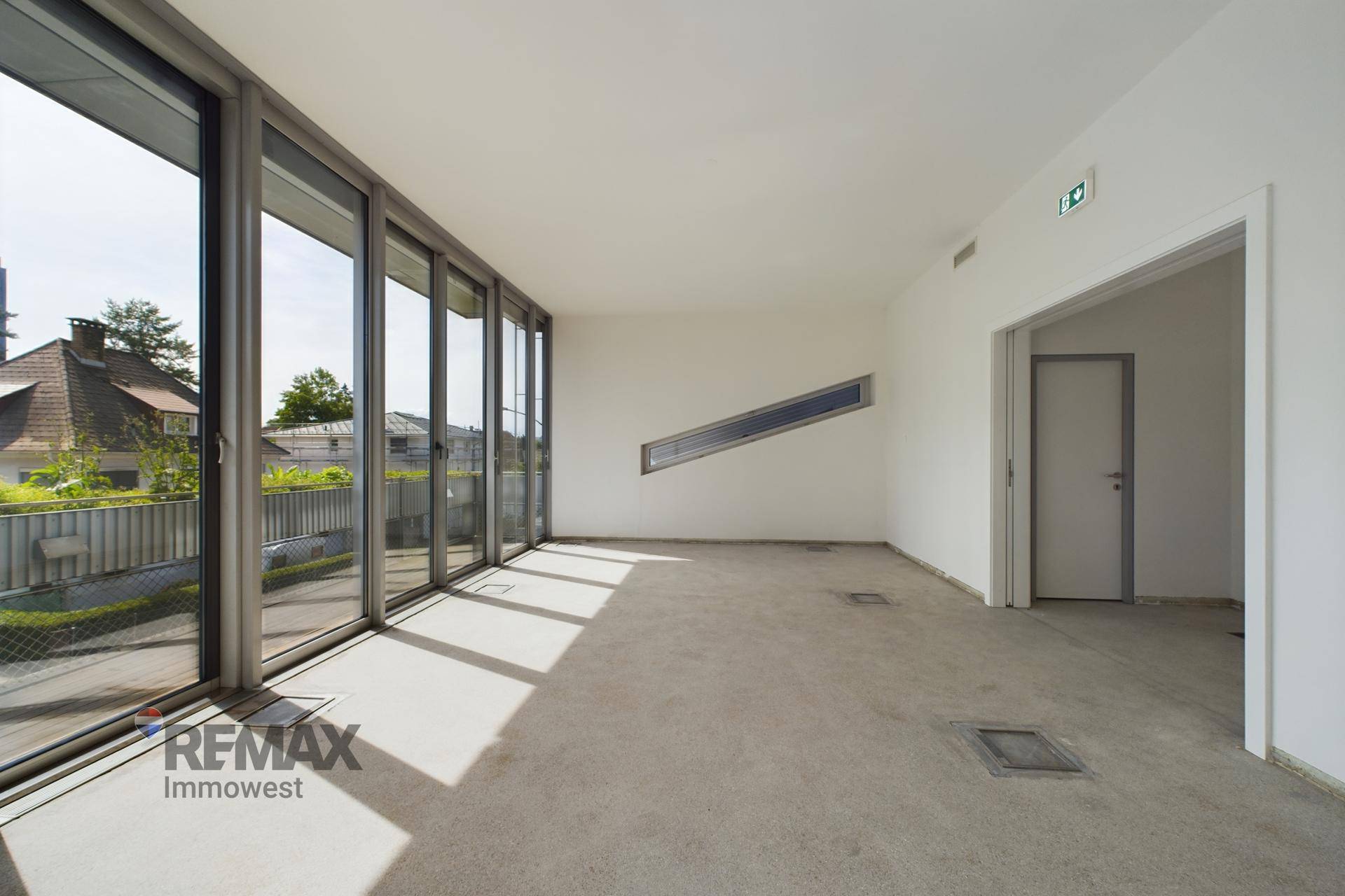 Heller Büroraum mit großen Fenstern und einem schrägen Fensterdetail, das viel Licht spendet.
