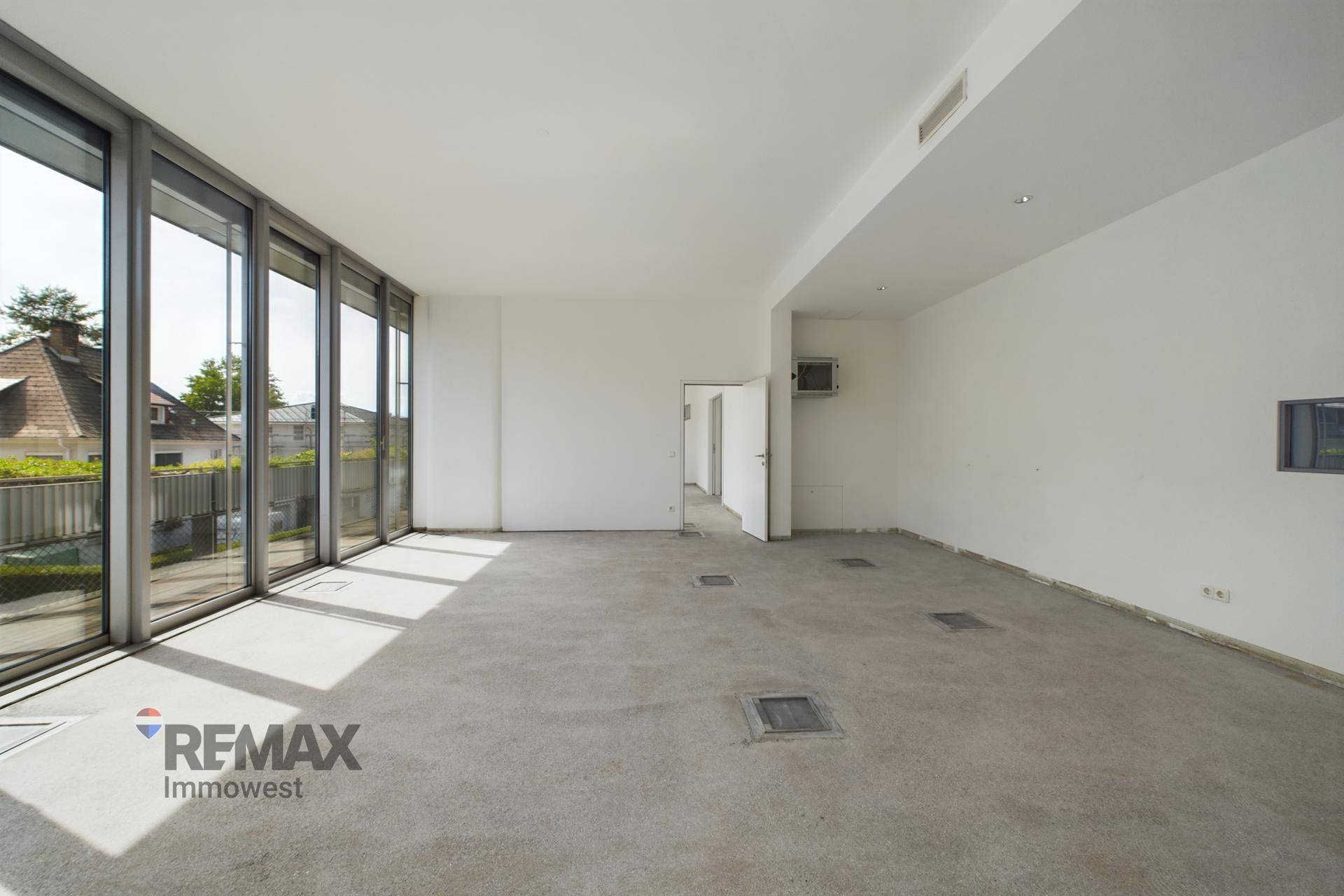 Weitläufiger, heller Raum mit großen Fenstern und einem offenen Grundriss, ideal für Büronutzung.