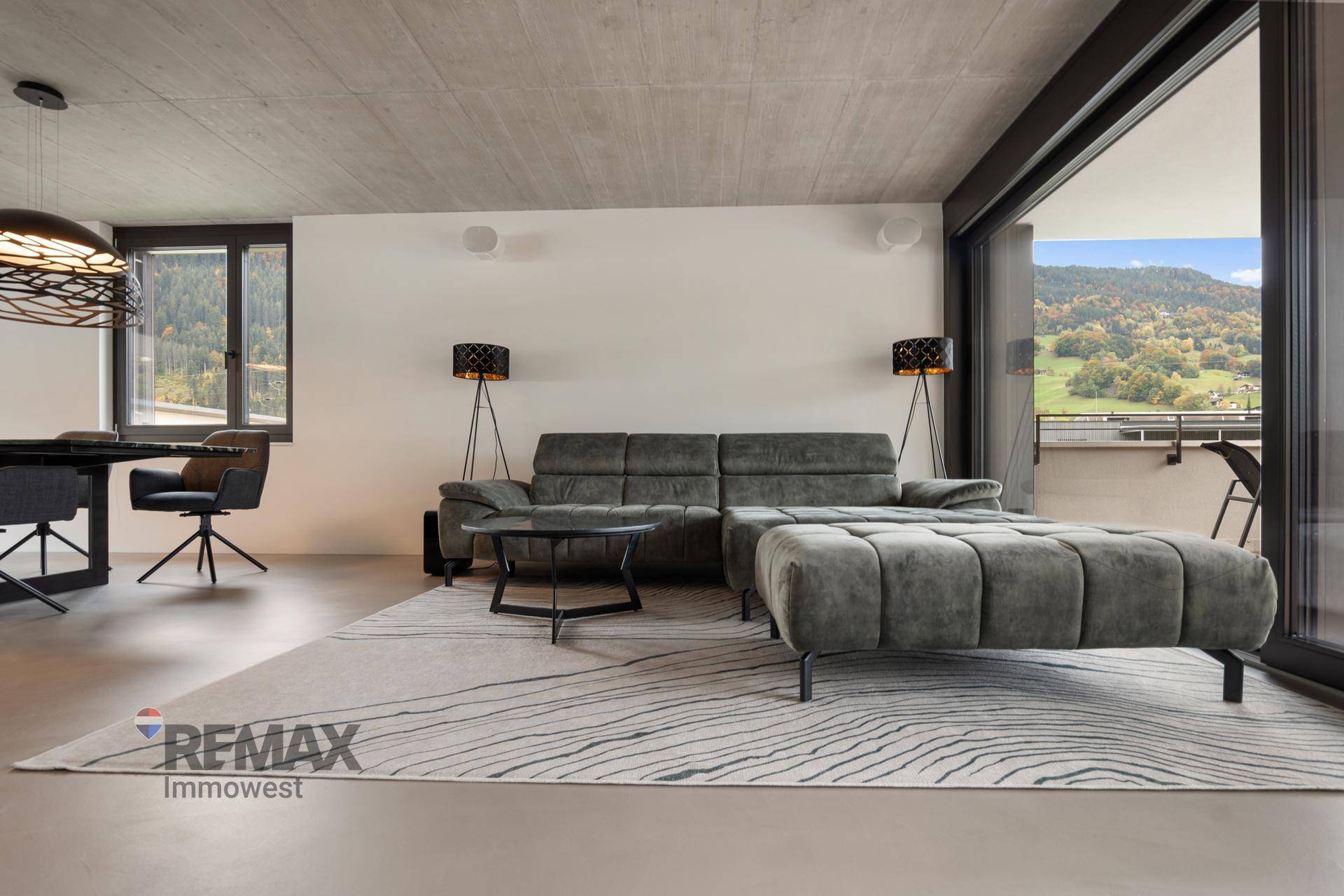 Gemütlicher Wohnbereich mit großem Ecksofa, modernem Teppich und Schiebetüren zum Balkon.