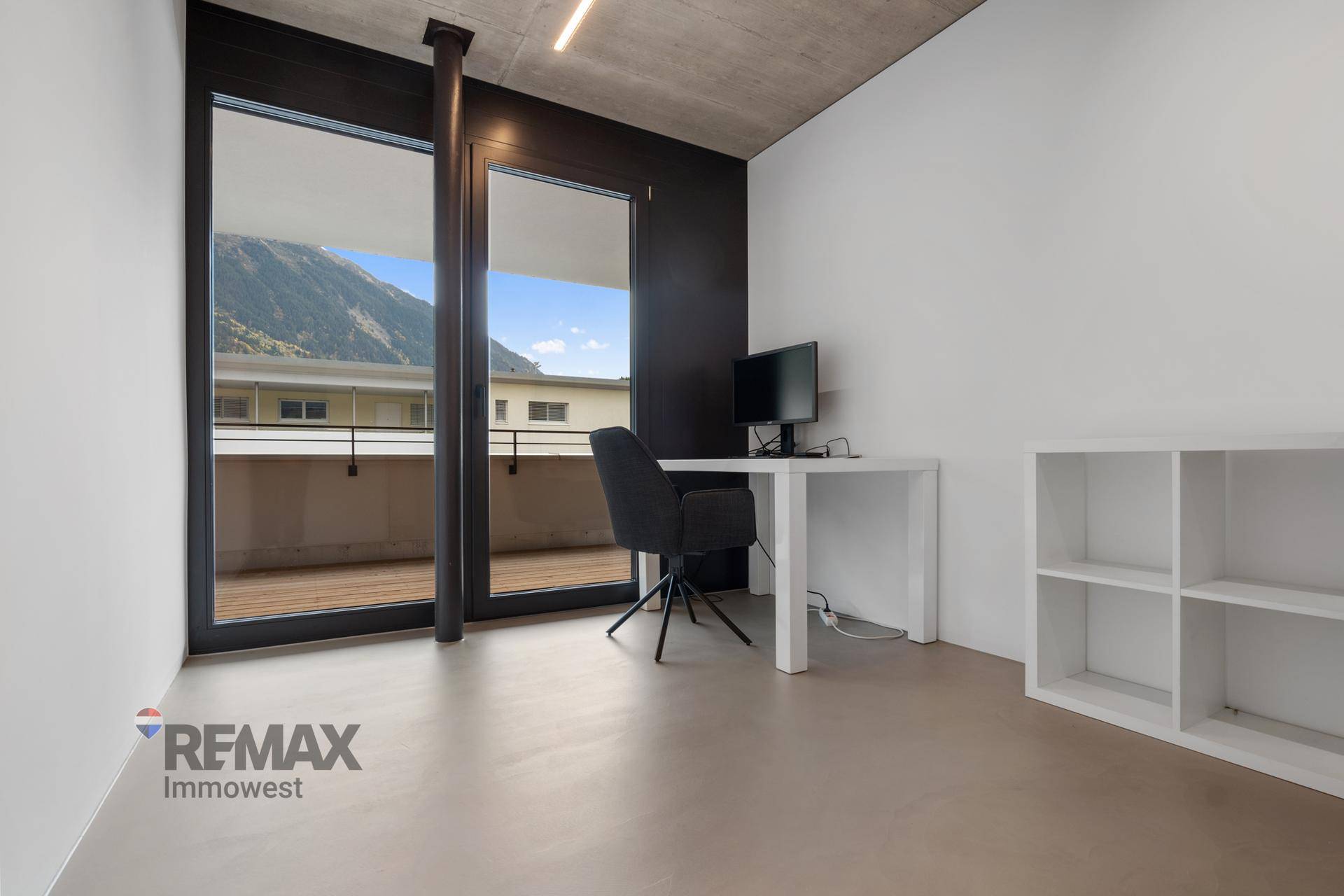 Modernes Arbeitszimmer mit Schreibtisch und Stuhl, bietet direkten Zugang zum Balkon mit schöner Aussicht.