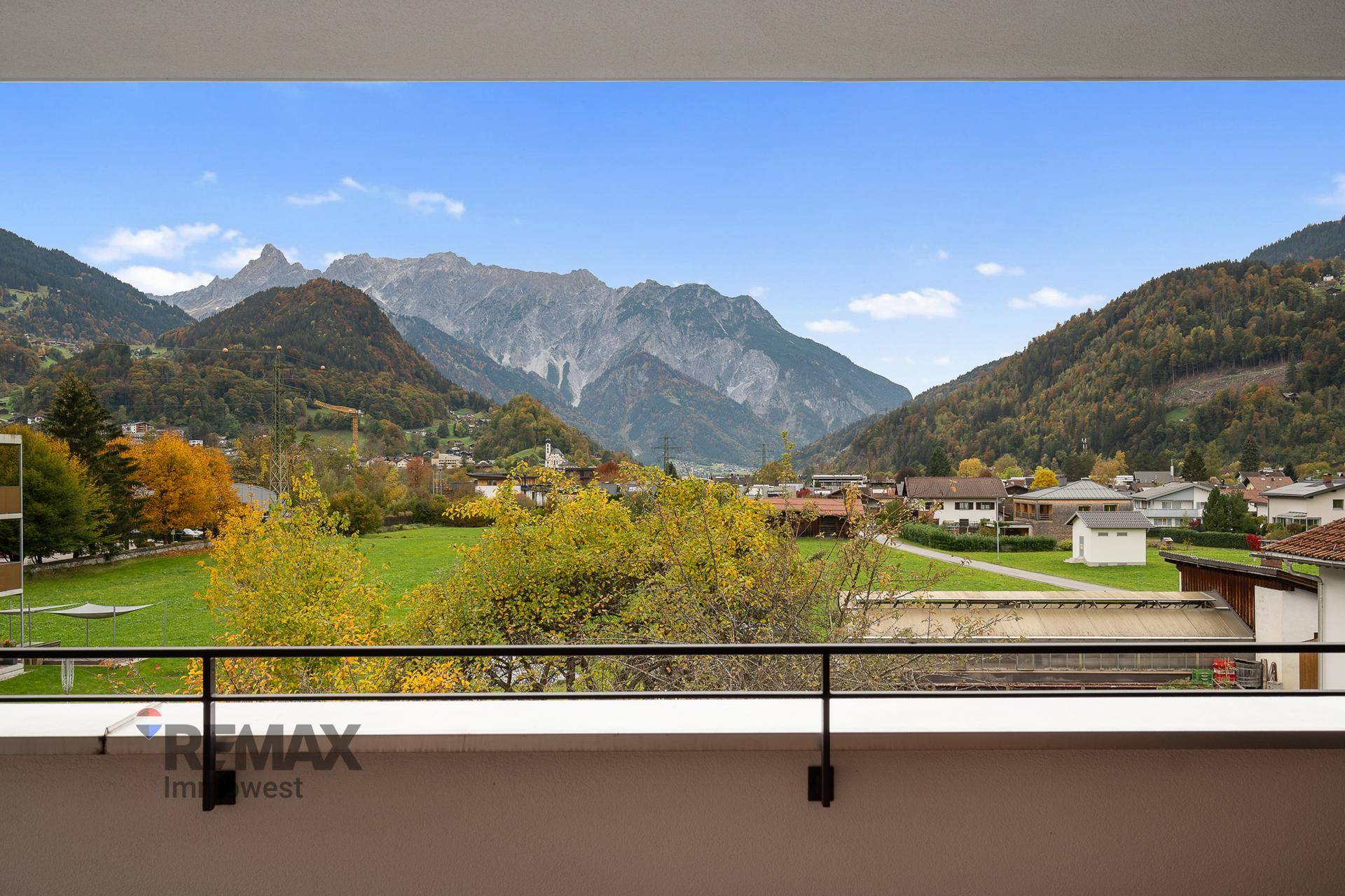 Panoramablick vom Balkon auf die majestätischen Berge und das grüne Tal mit Häusern.