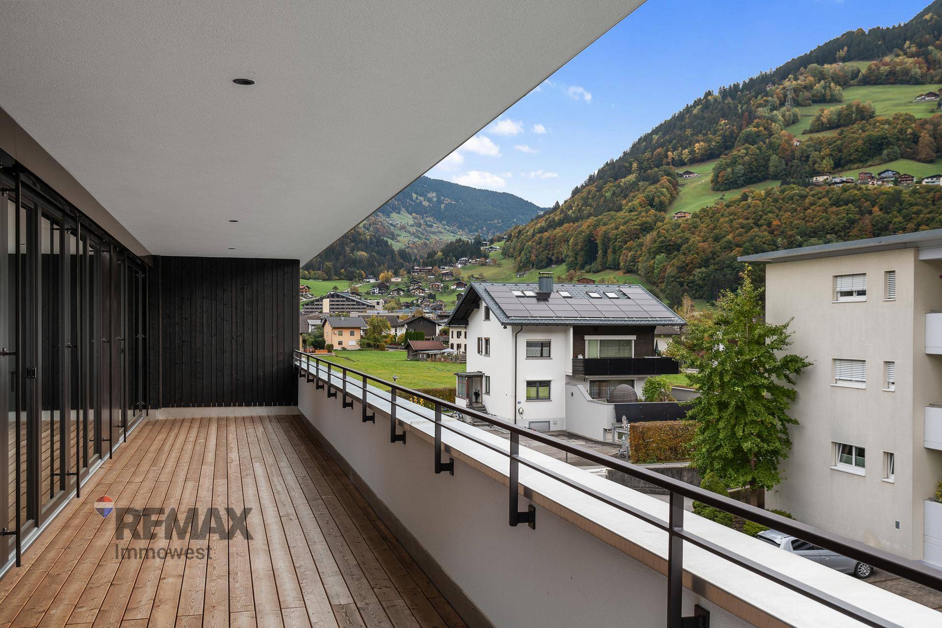 Geräumiger Holzbalkon mit Panoramablick auf die grünen Hügel und die alpine Umgebung.