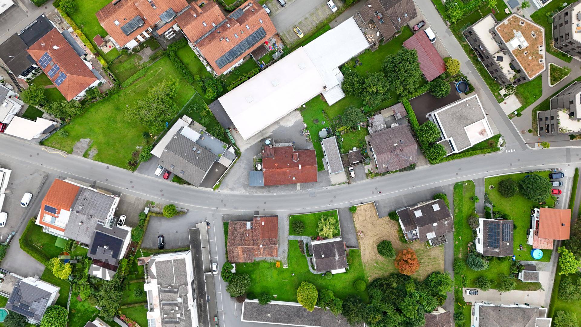 Luftaufnahme einer Wohnsiedlung mit Häusern, Gärten und Straßen, die die Umgebung zeigt.