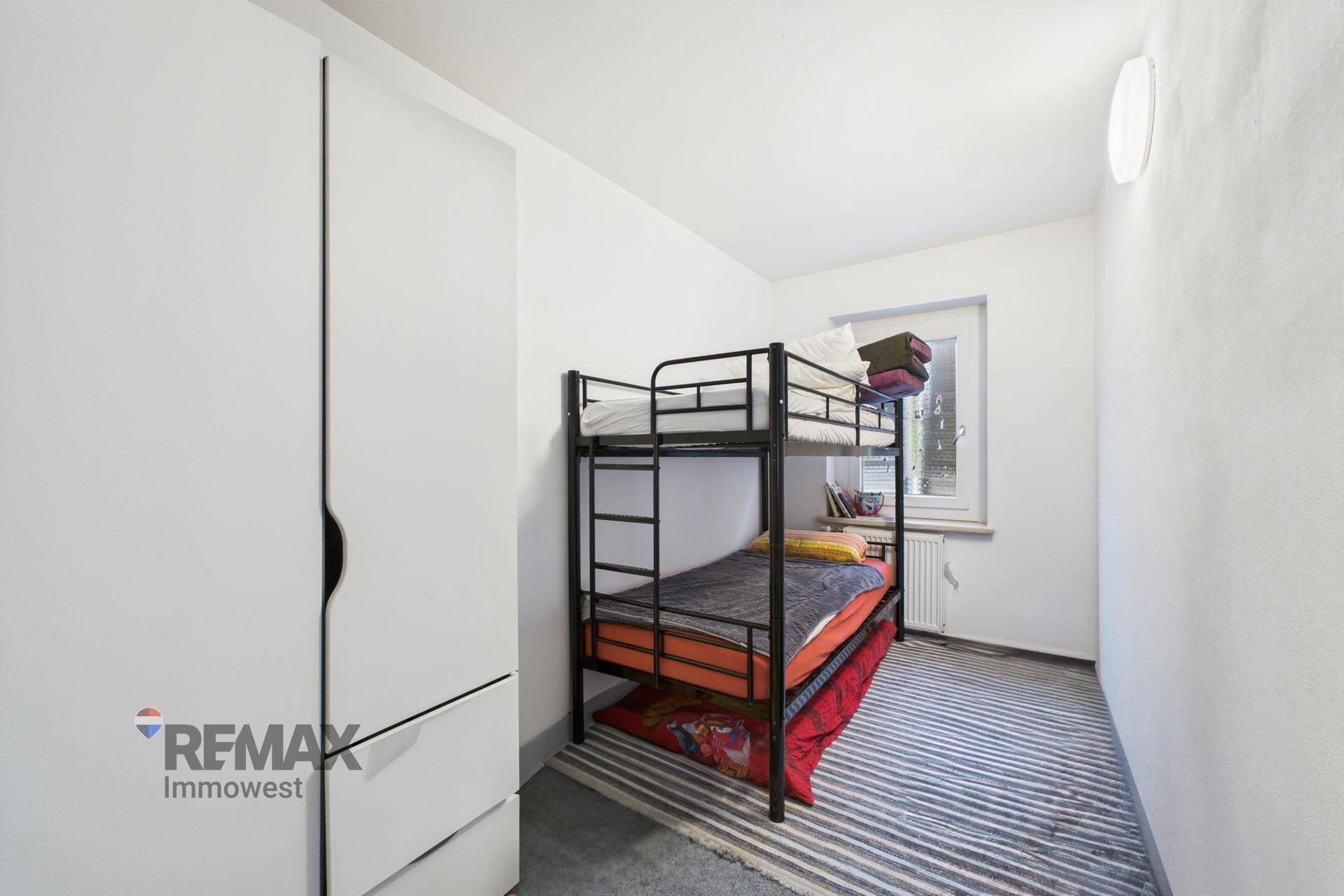 Kinderzimmer mit Etagenbett und Kleiderschrank, hell und funktional eingerichtet.