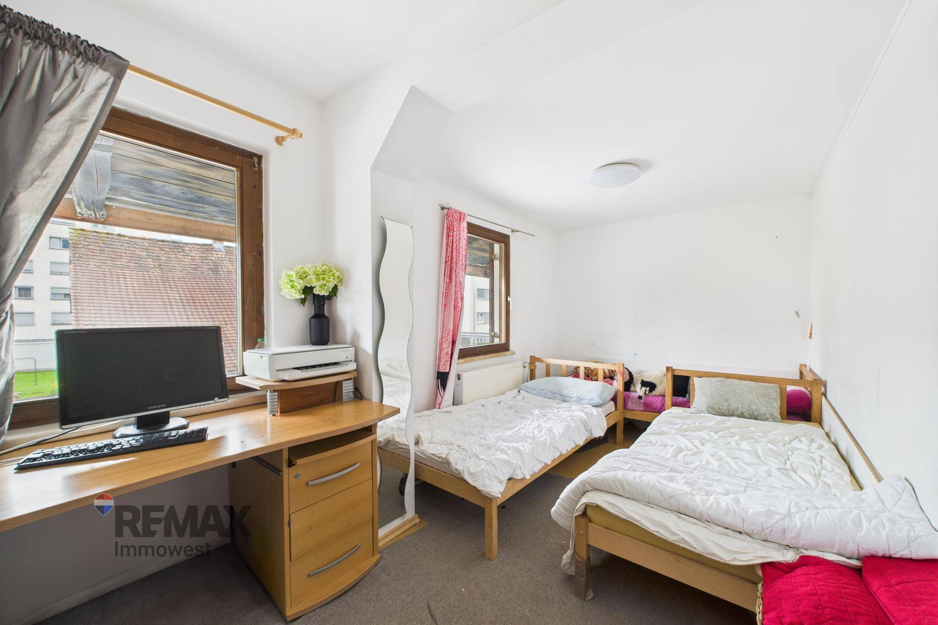 Schlafzimmer mit zwei Einzelbetten und Schreibtisch, hell und funktional eingerichtet.