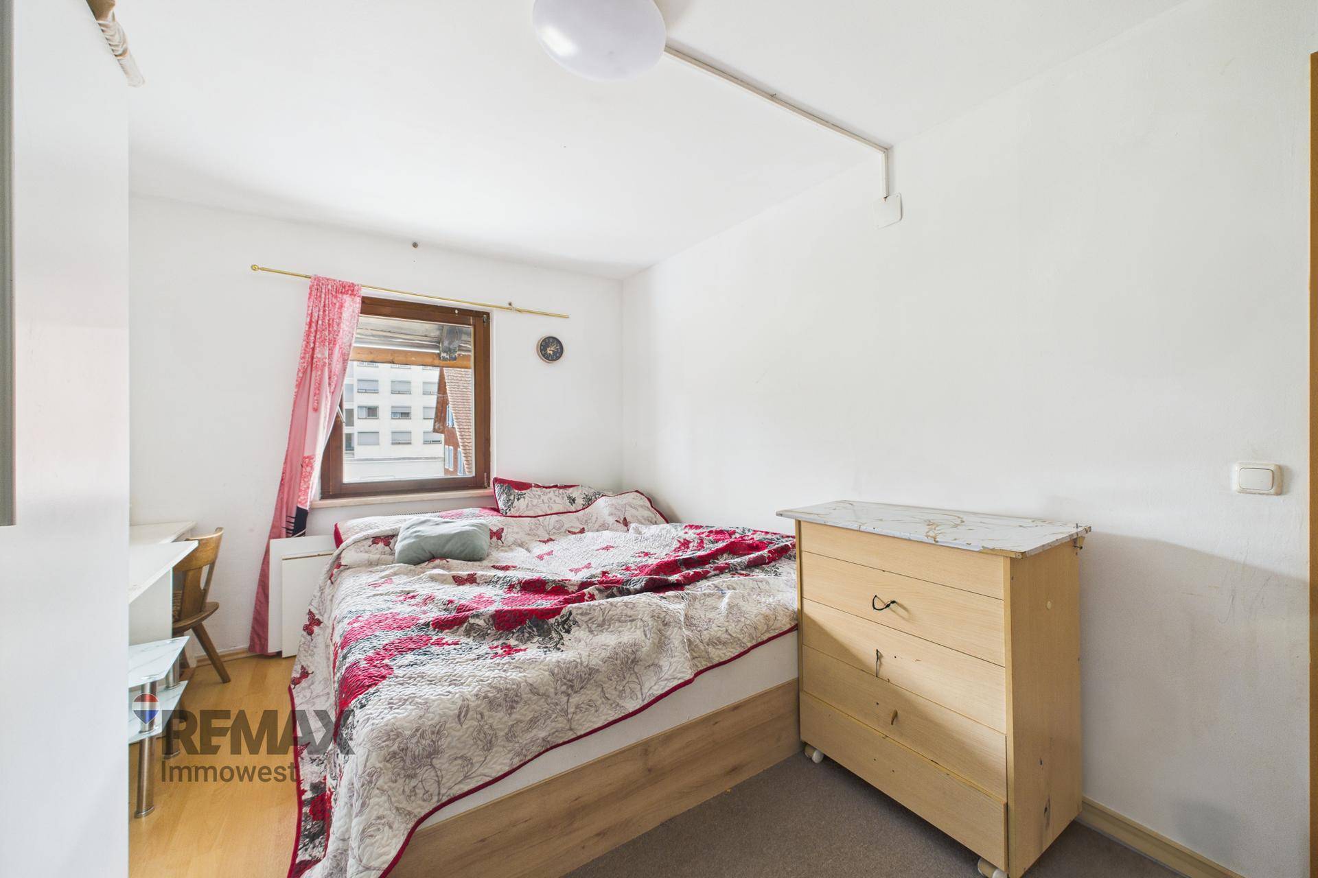 Schlafzimmer mit Doppelbett und Kommode, hell und einfach eingerichtet.