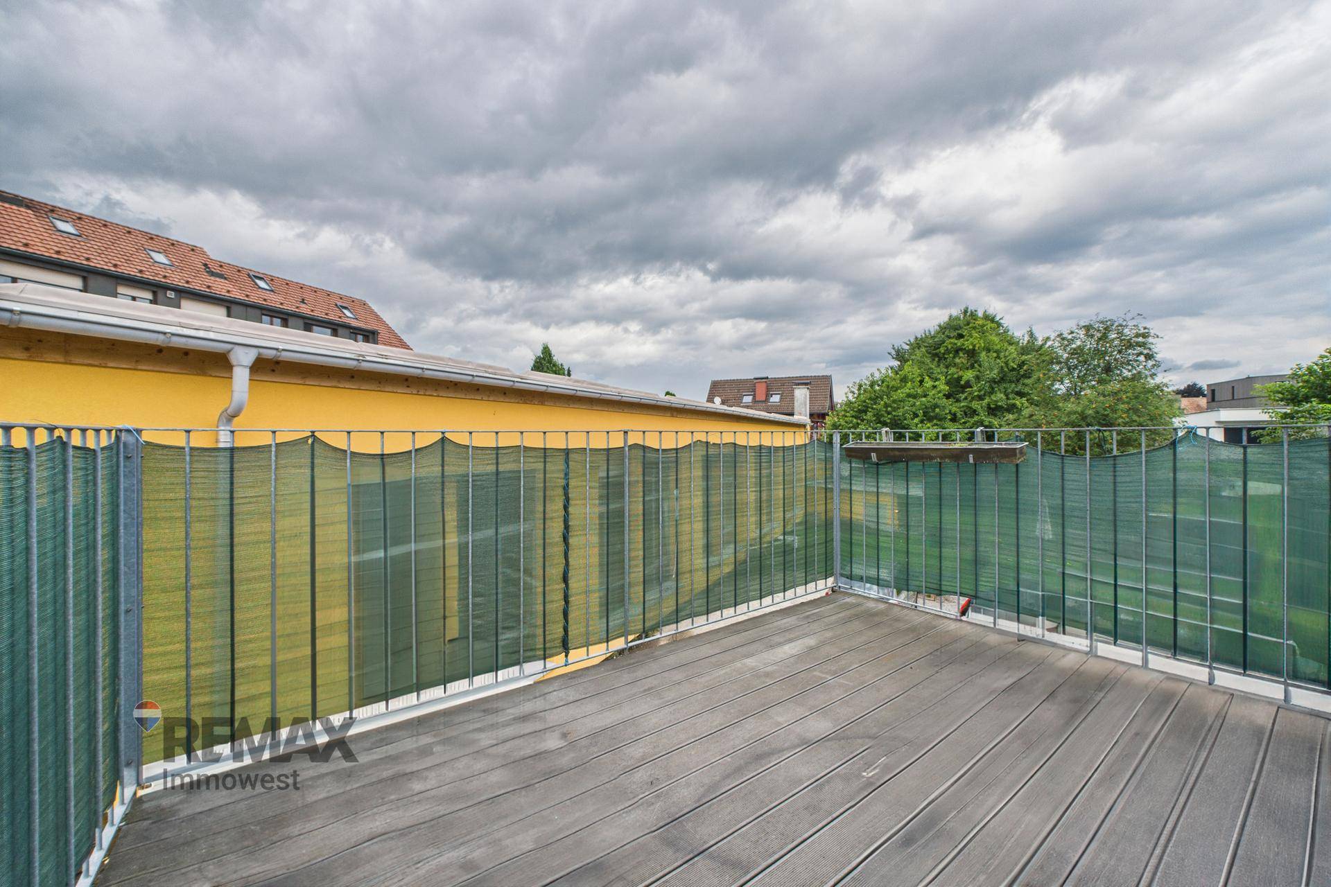 Geräumige Terrasse mit Holzboden und Sichtschutz, ideal für entspannte Stunden im Freien.