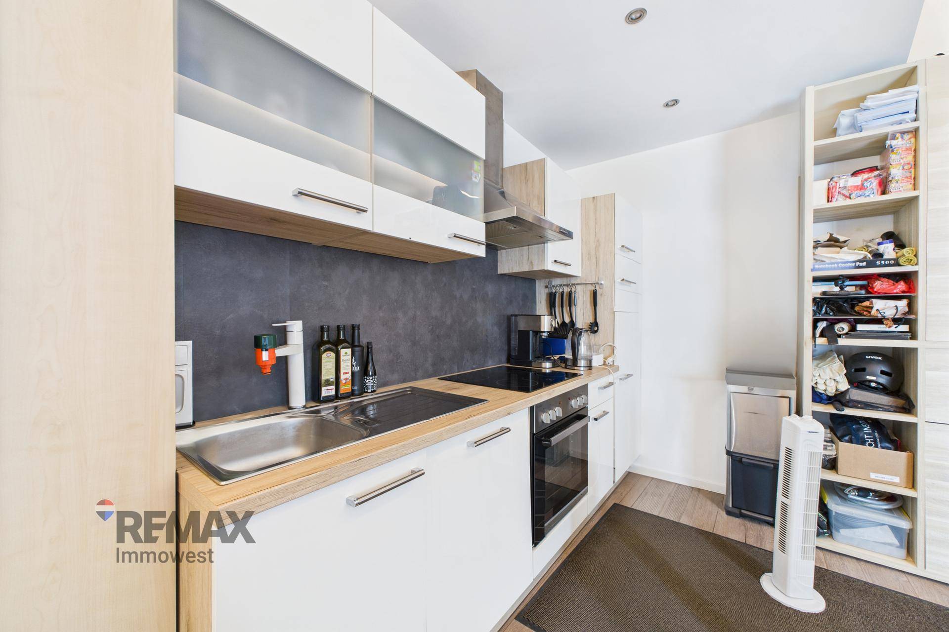Moderne Küche mit weißen Schränken, Holzdetails und integrierten Geräten, gut ausgestattet.