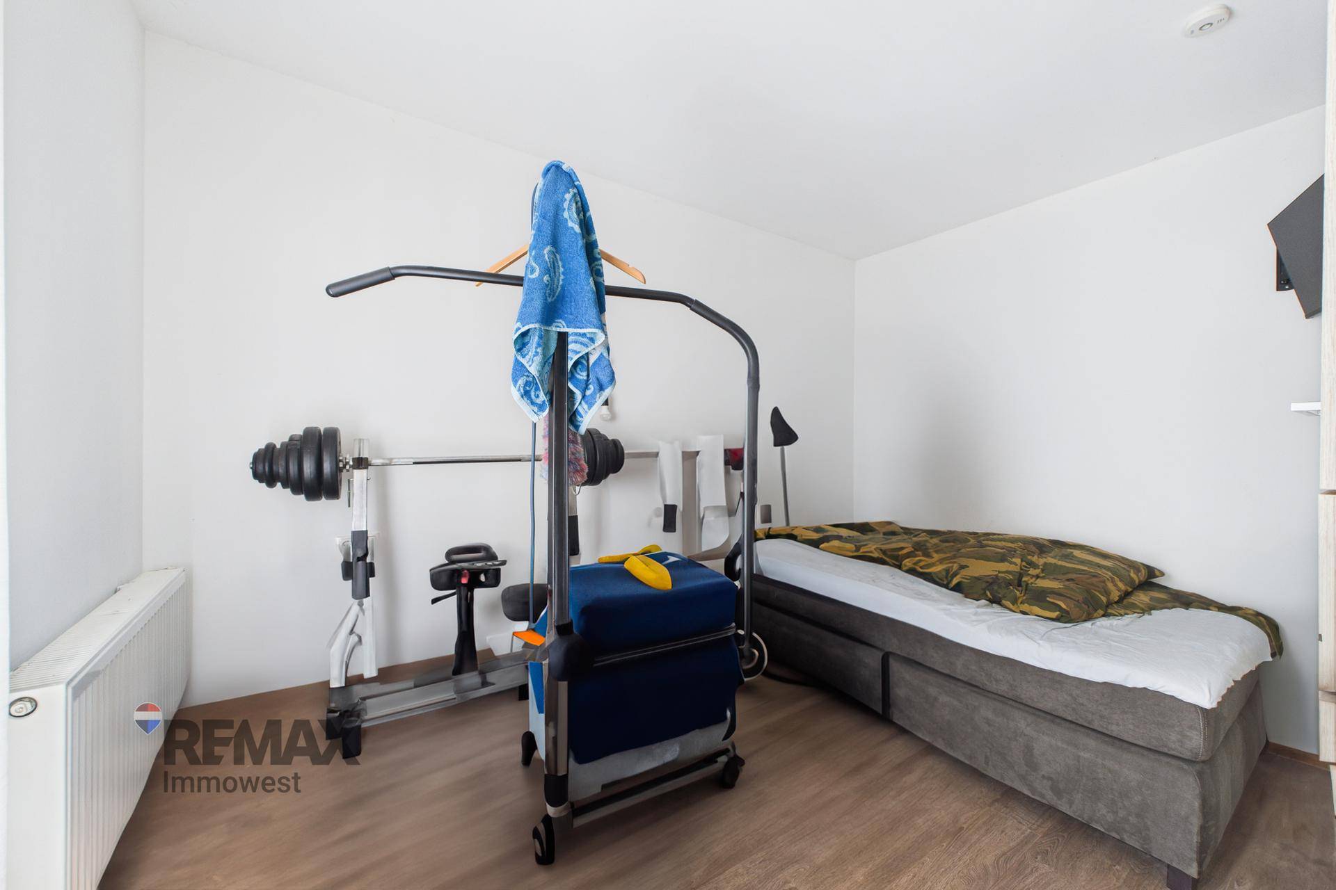 Raum mit Fitnessgeräten und Bett, als Schlafzimmer und Trainingsbereich genutzt.