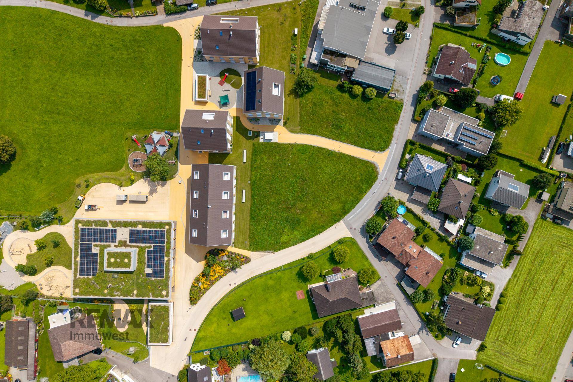 Überblick über eine moderne Wohnsiedlung mit Neubauten, Grünflächen und Photovoltaikanlagen.