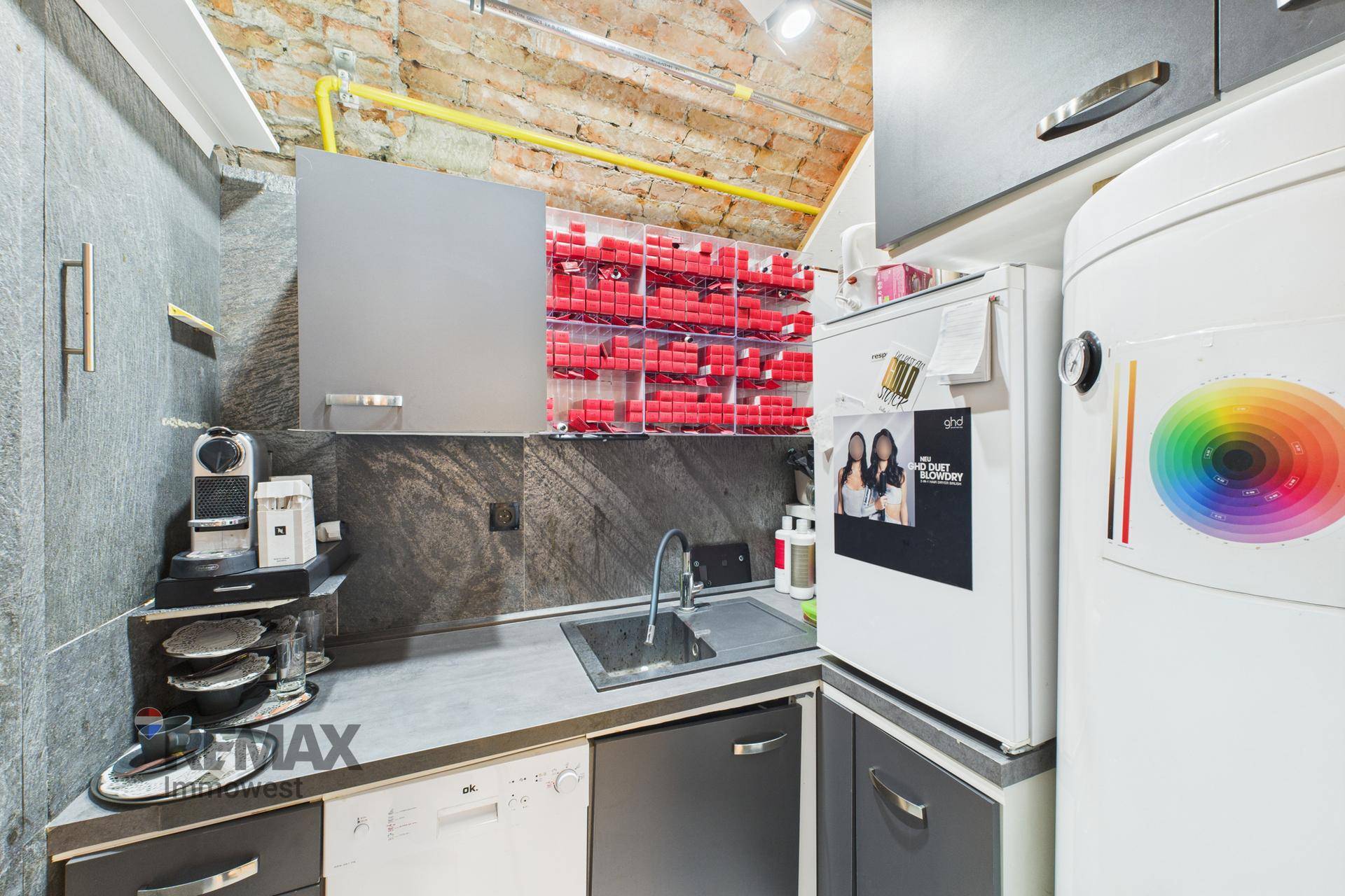 Kleine Küchenzeile mit Spüle, Kühlschrank und Stauraum in einem funktionalen Bereich.