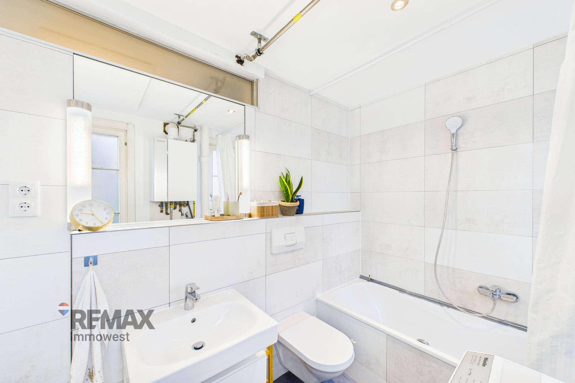 Modernes Badezimmer mit Waschbecken, Toilette und Badewanne in hellen Fliesen.