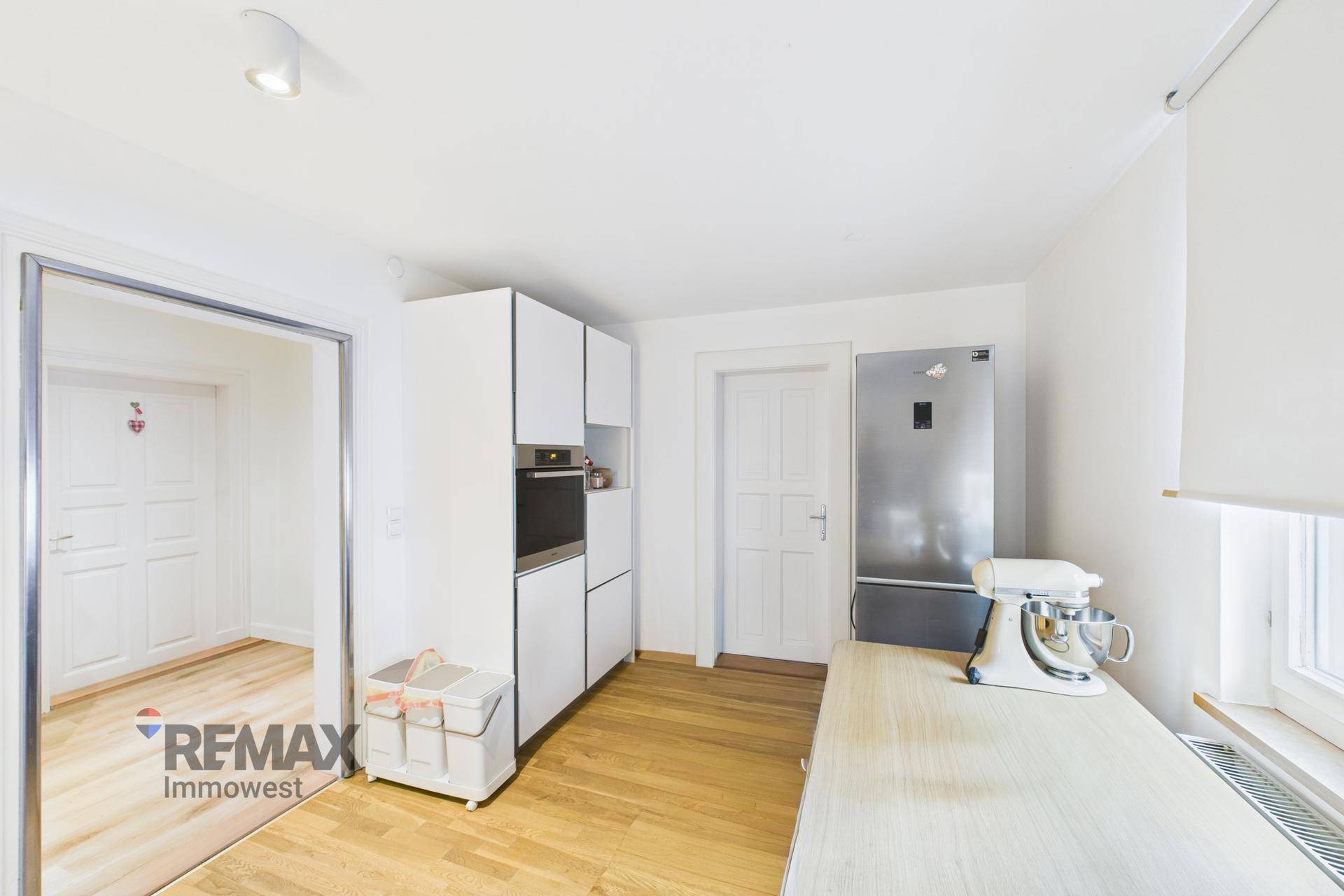 Funktionale Küche mit weißen Einbauschränken, Backofen und großem Kühlschrank.