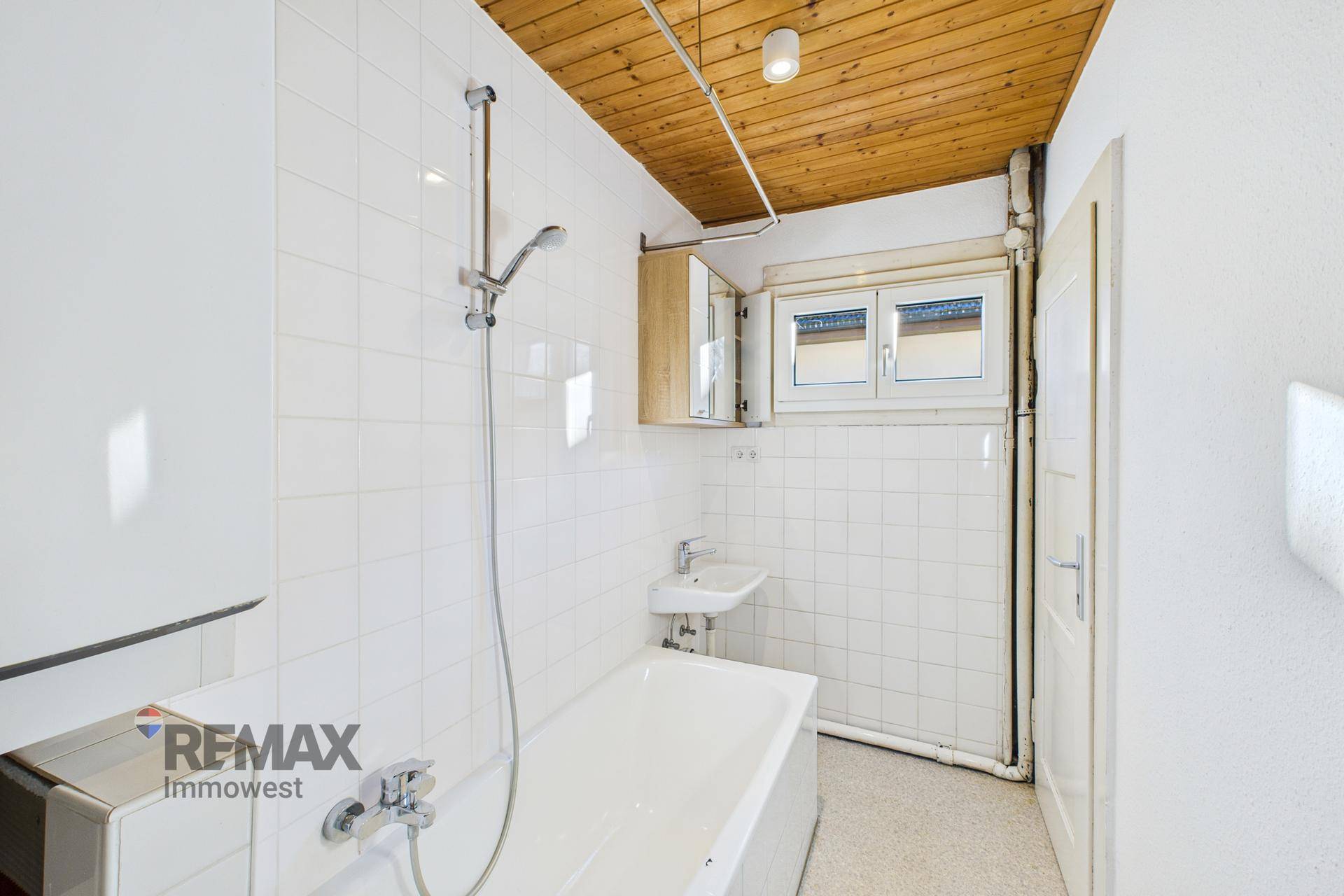 Badezimmer mit Badewanne, Dusche, Waschbecken und Holzdecke.