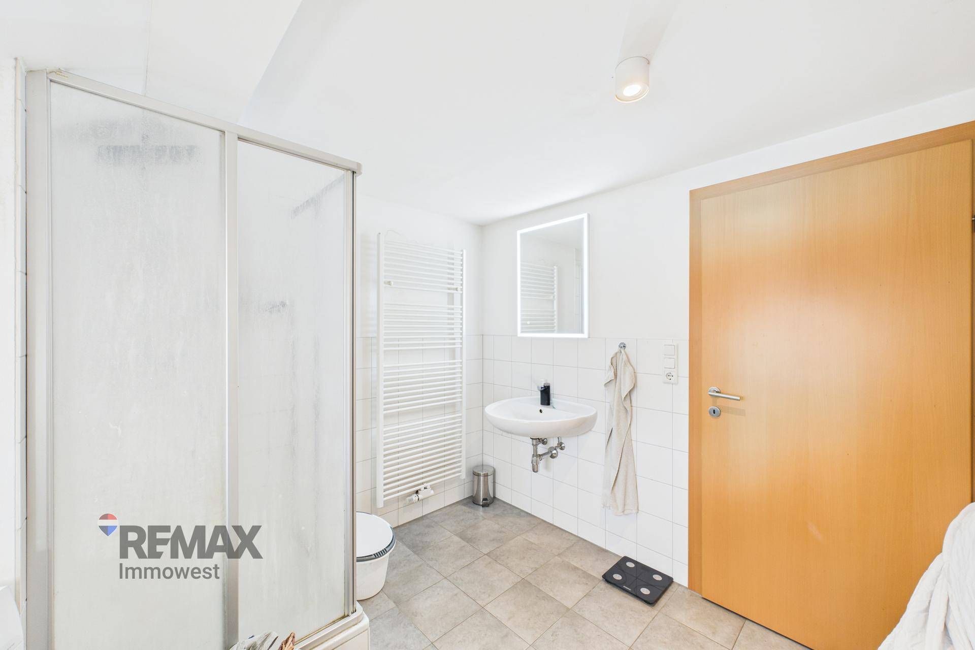 Helles Badezimmer mit Duschkabine, modernem Waschbecken und beheiztem Handtuchhalter.