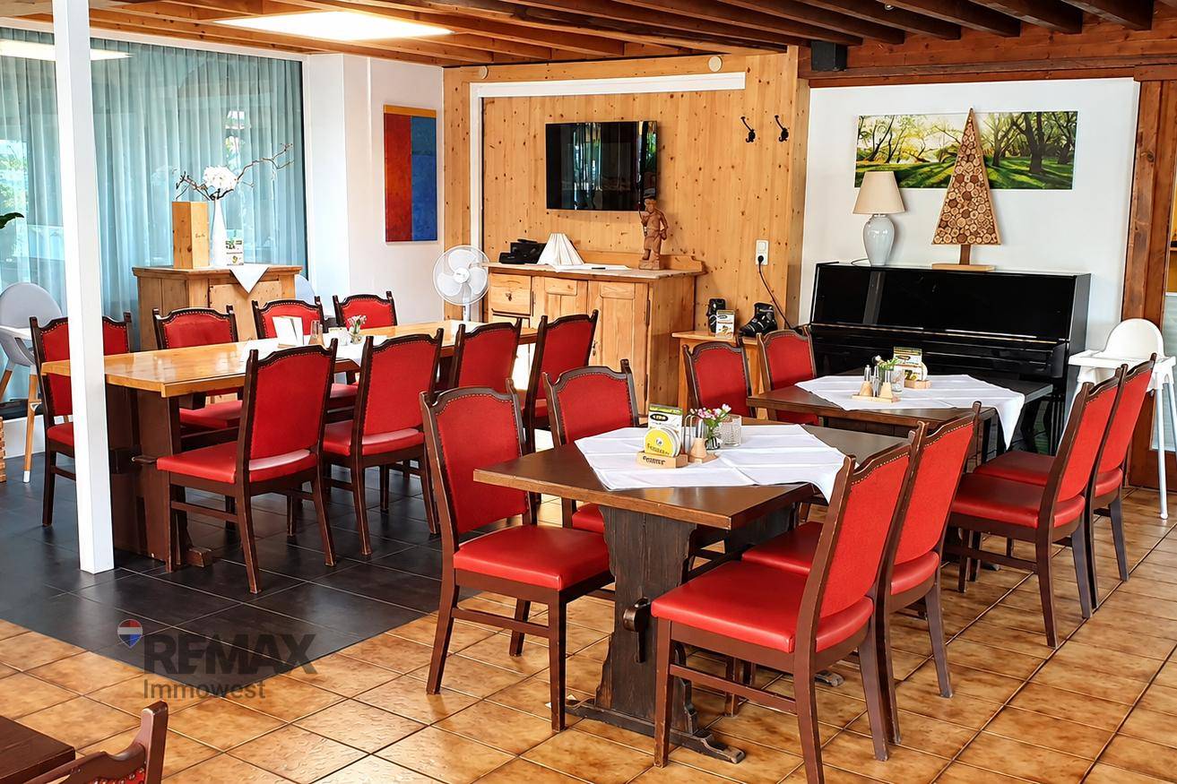 Geräumiger Speisesaal mit Holztischen, roten Stühlen und einer gemütlichen Atmosphäre für Gäste.