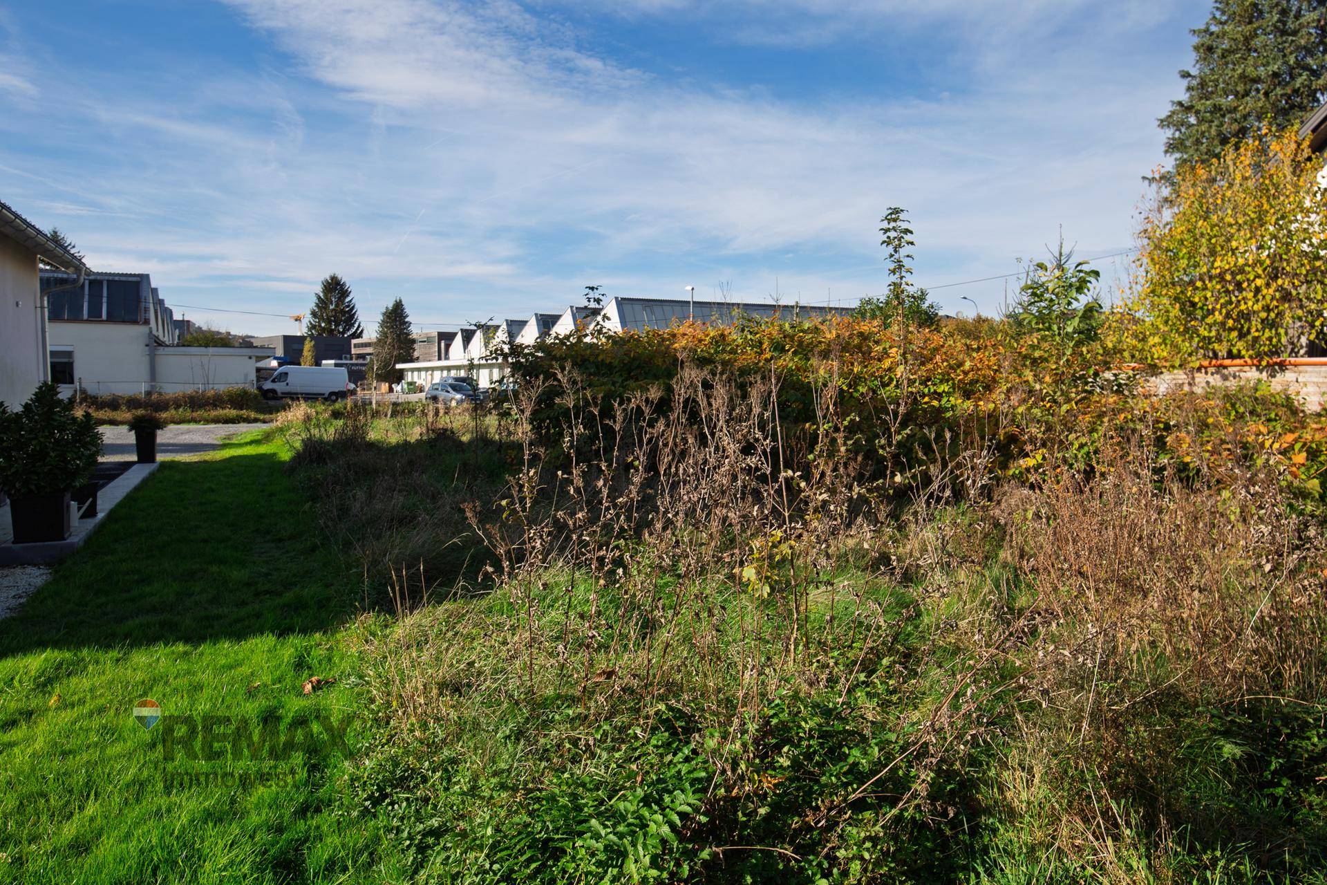 Unbebautes Grundstück mit hohem Gras und Blick auf die umliegende Wohnbebauung.