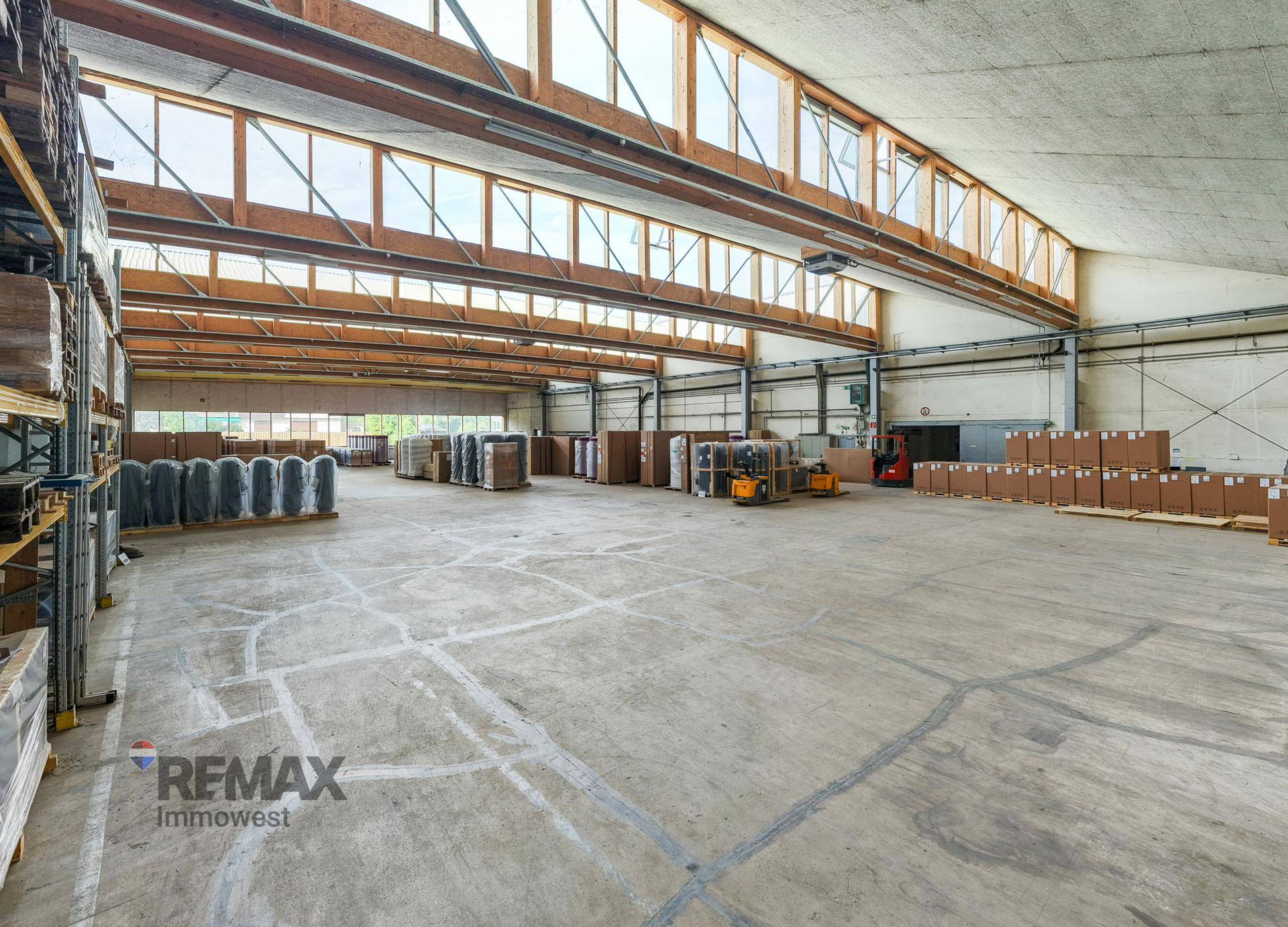 Weitläufige Lagerhalle mit viel Tageslicht durch die hohen Fenster und einer robusten Bauweise.