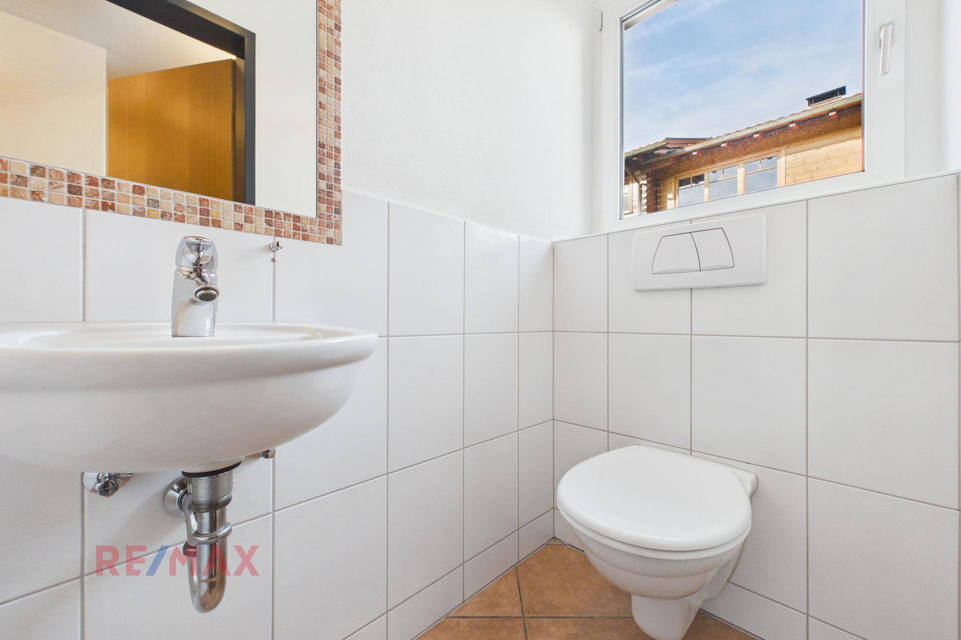 Kleines Gäste-WC mit weiß gefliesten Wänden, Einzelwaschbecken und Fenster.