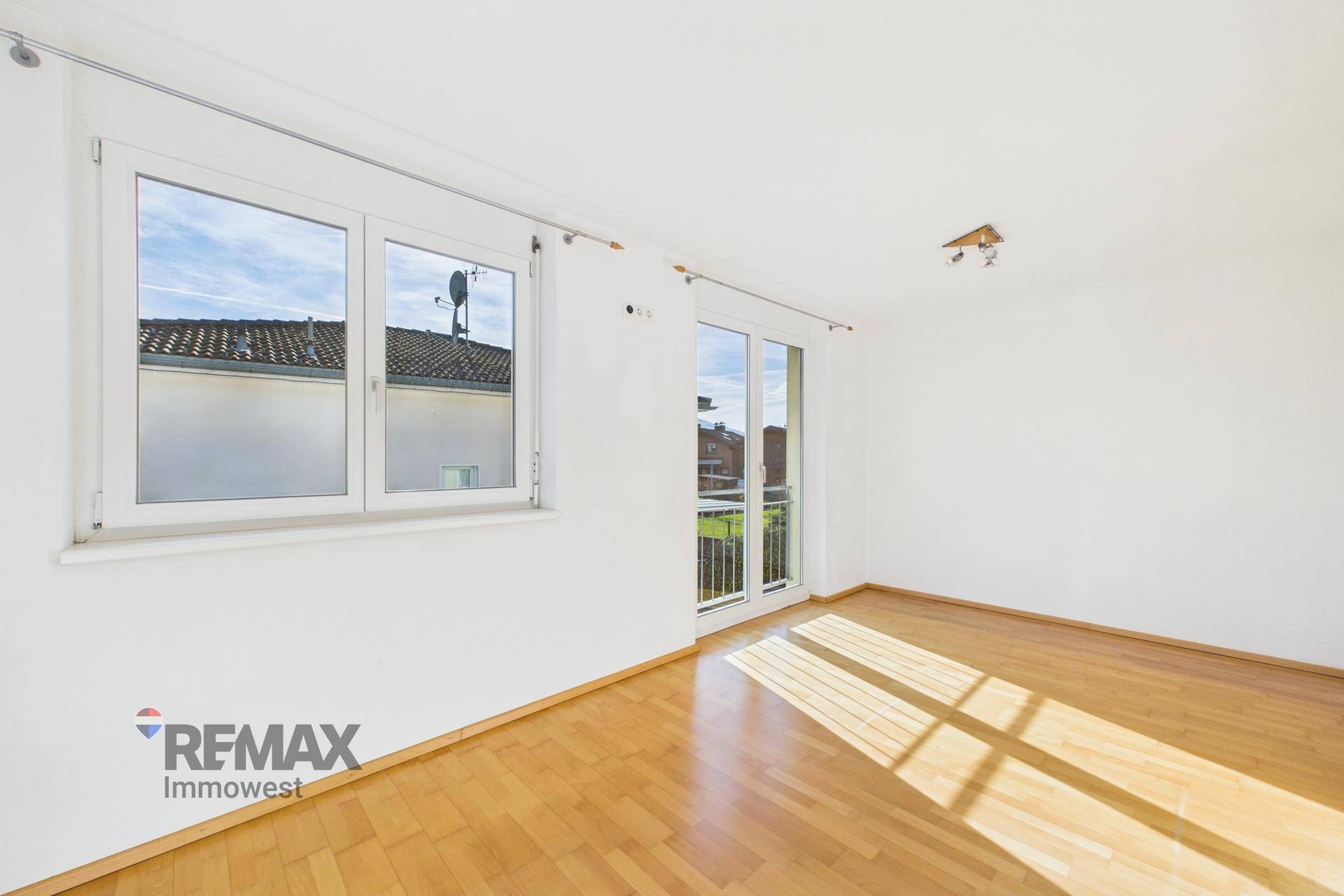 Geräumiges Zimmer mit Parkettboden und Fenster, das viel Sonnenlicht hereinlässt.