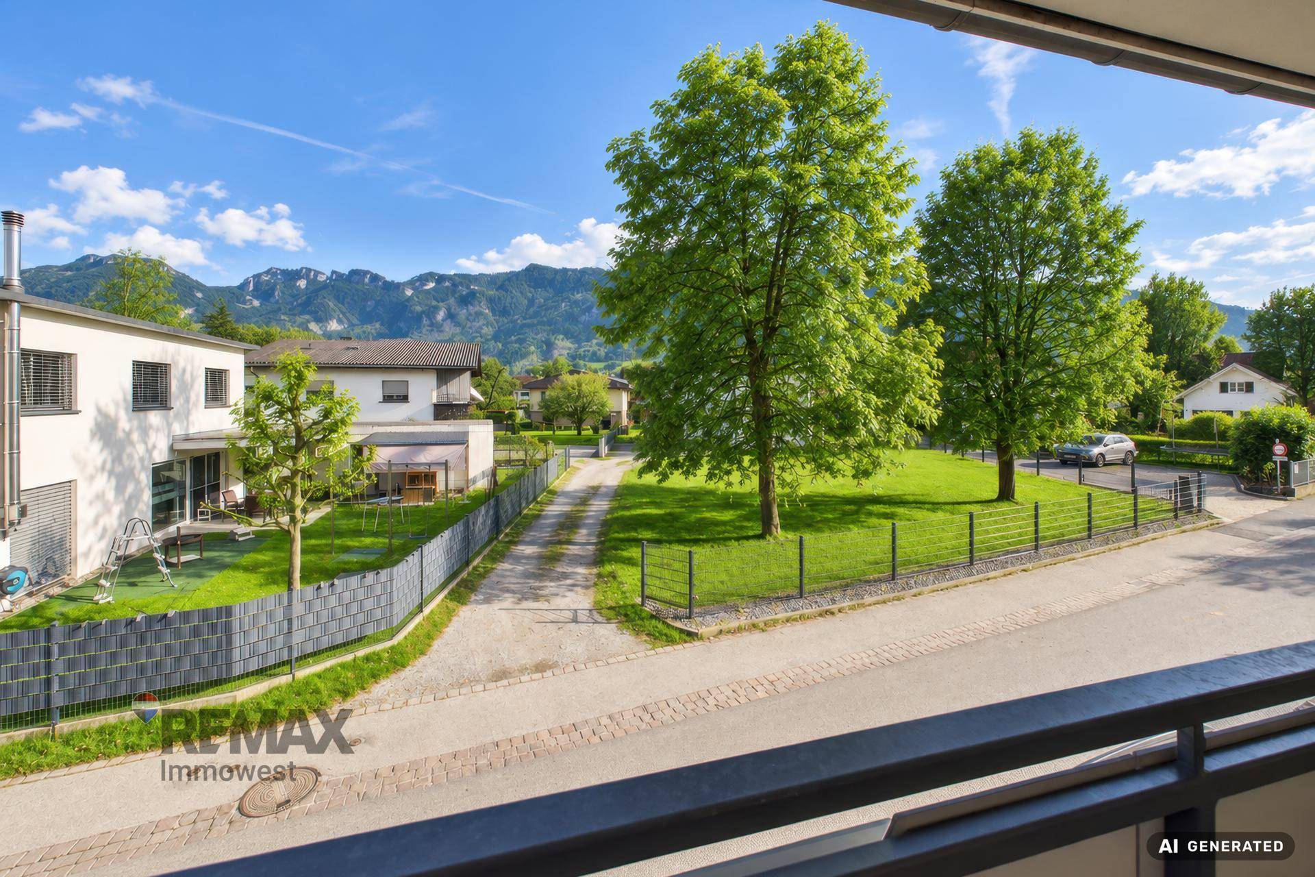 Weitläufiger Blick vom Balkon auf eine grüne Wiese und die umliegende Berglandschaft.