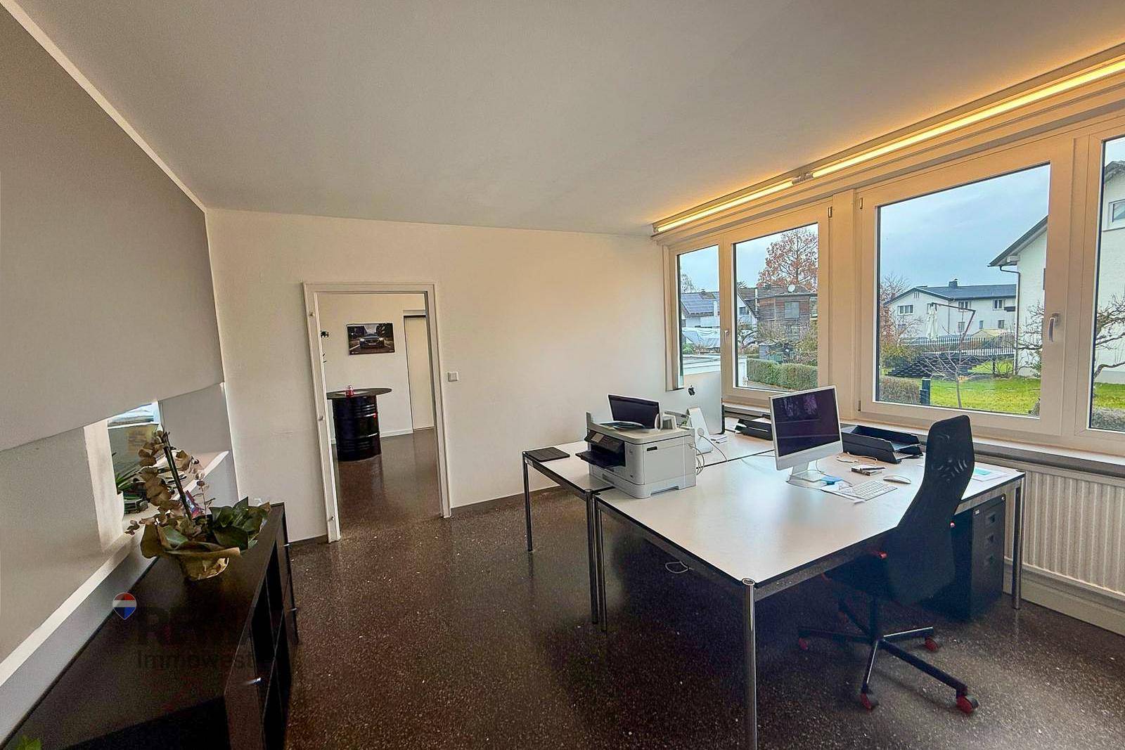 Großes Büro mit mehreren Arbeitsplätzen, großen Fenstern und Blick auf die umliegende Bebauung.