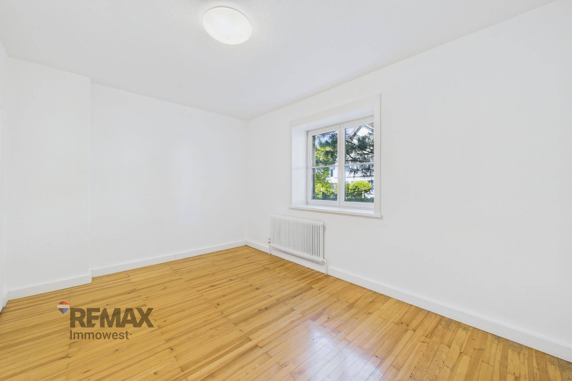 Gemütliches Zimmer mit Fenster und Holzfußboden, ideal als Schlaf- oder Arbeitszimmer nutzbar.
