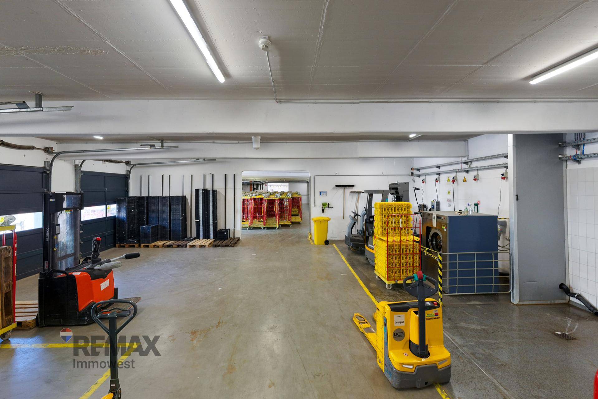 Innenansicht eines Lagerbereichs mit Betonboden, Rolltoren und Gabelstaplern.