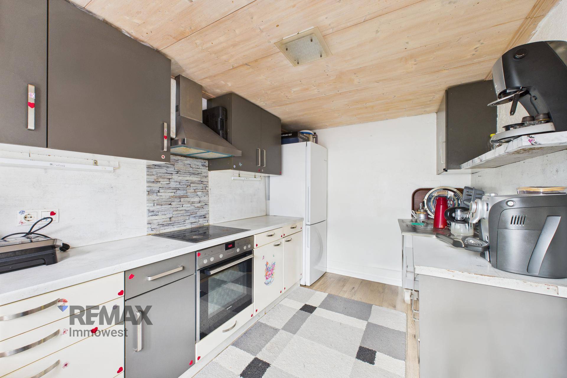 Funktionale Küche mit Holzdecke, Arbeitsplatte und verschiedenen Küchengeräten.