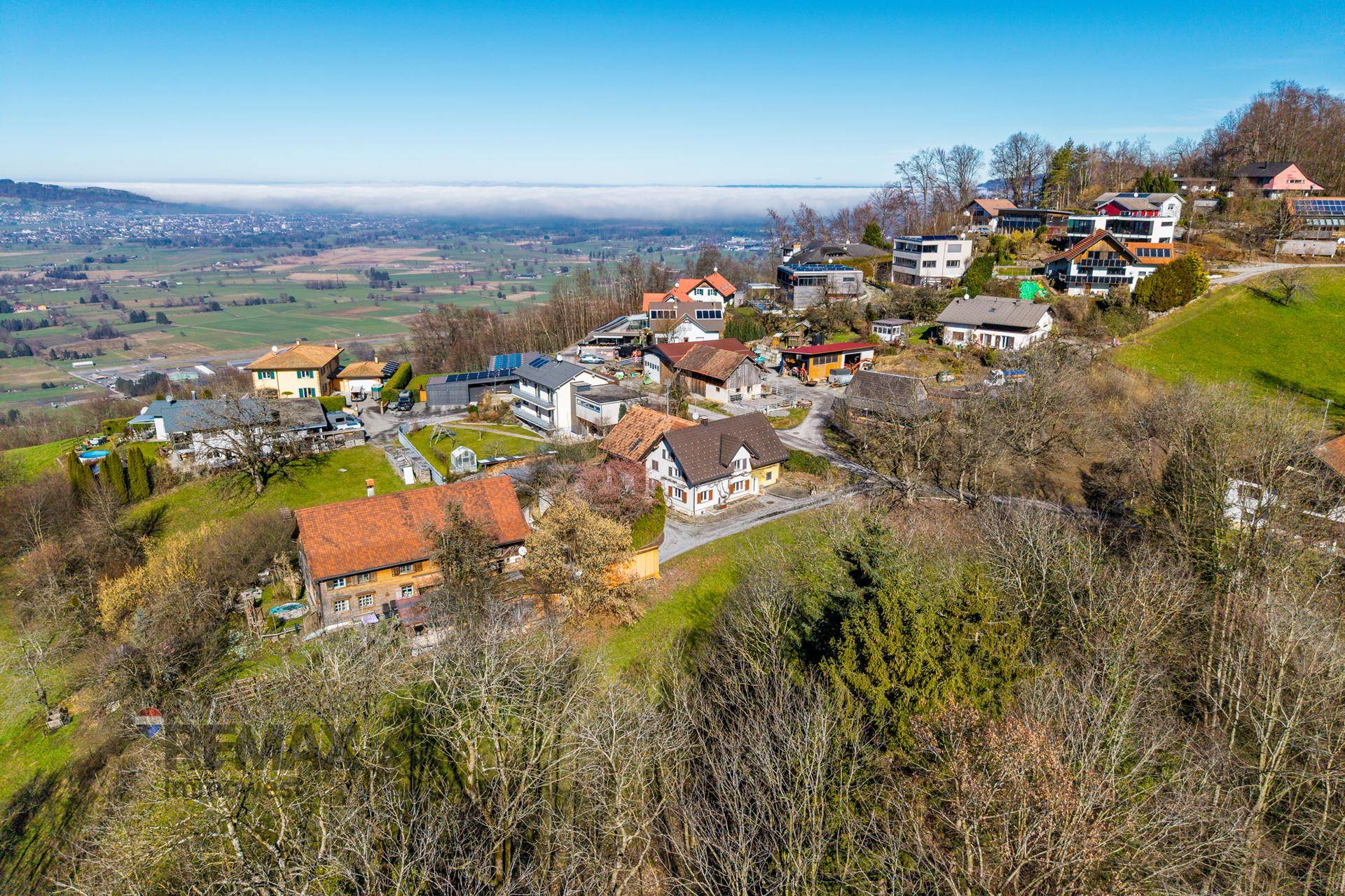 Weitläufige Luftaufnahme des Grundstücks in einer hügeligen Landschaft mit Fernblick.