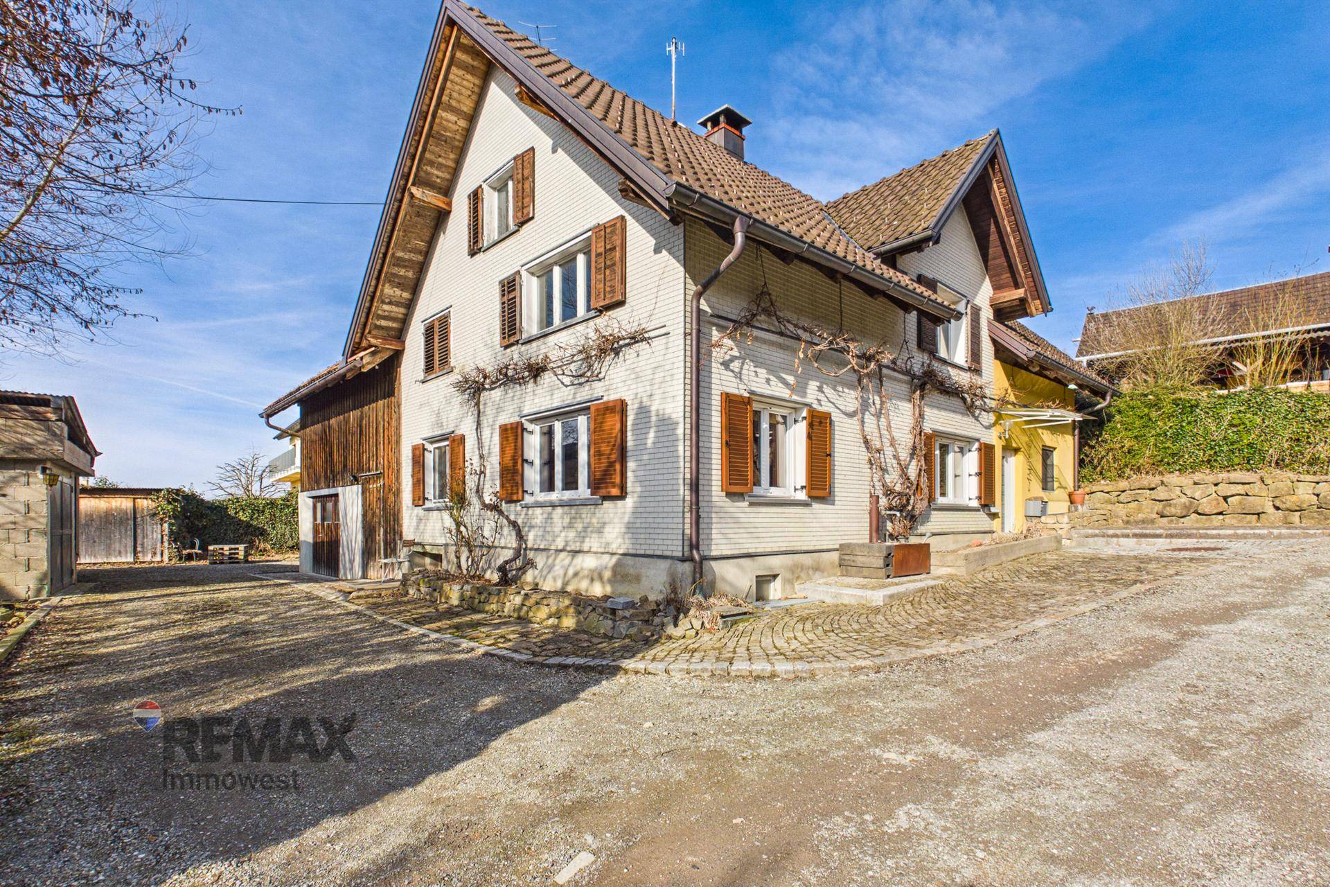 Ansicht des Haupthauses von der Einfahrt aus mit traditionellen Holzfensterläden.