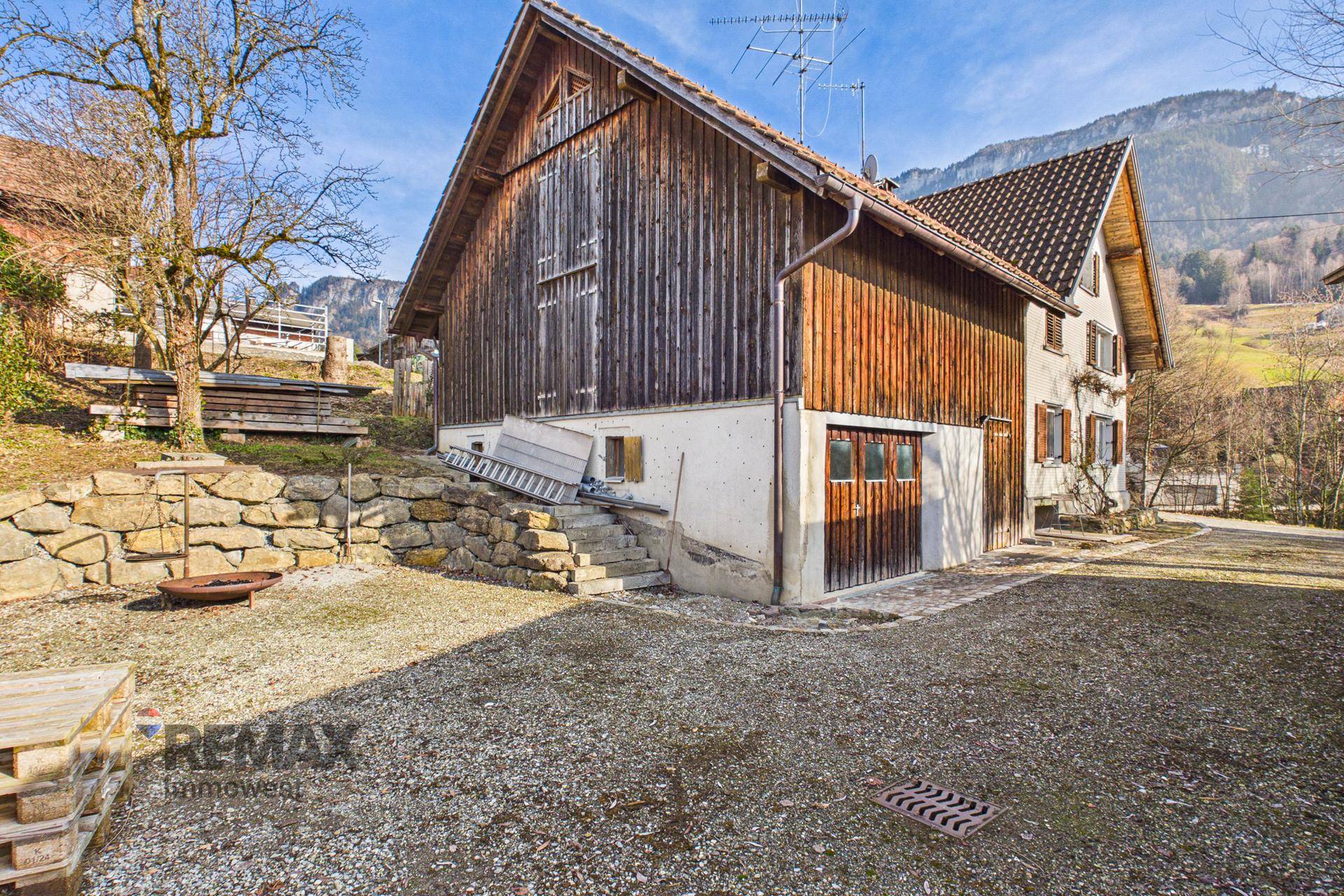 Seitenansicht des Hauses mit Holzanbau und Blick auf die umliegenden Berge.