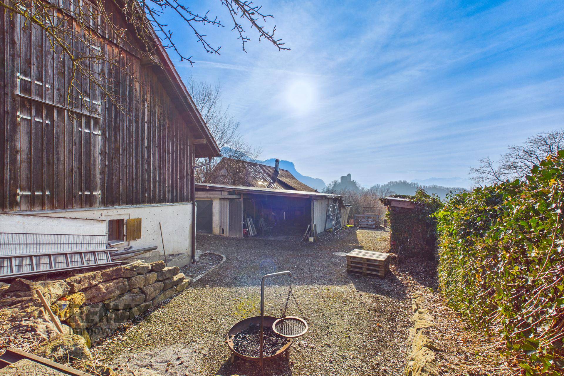 Gartenbereich mit Feuerstelle und Hecke, ideal für gemütliche Abende im Freien.