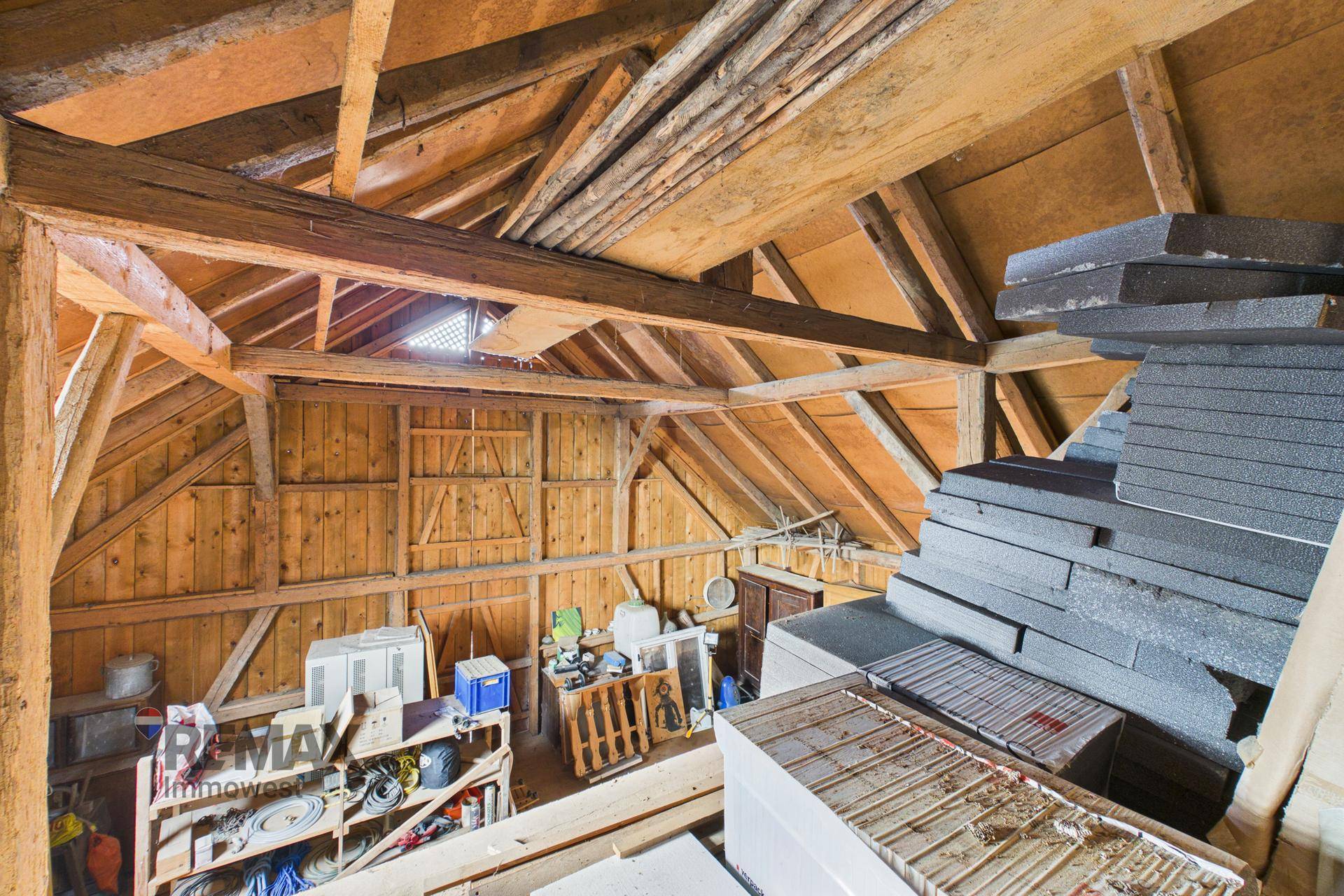 Geräumiger Dachboden mit sichtbaren Holzbalken und Holzverkleidung, ideal als Lagerfläche.