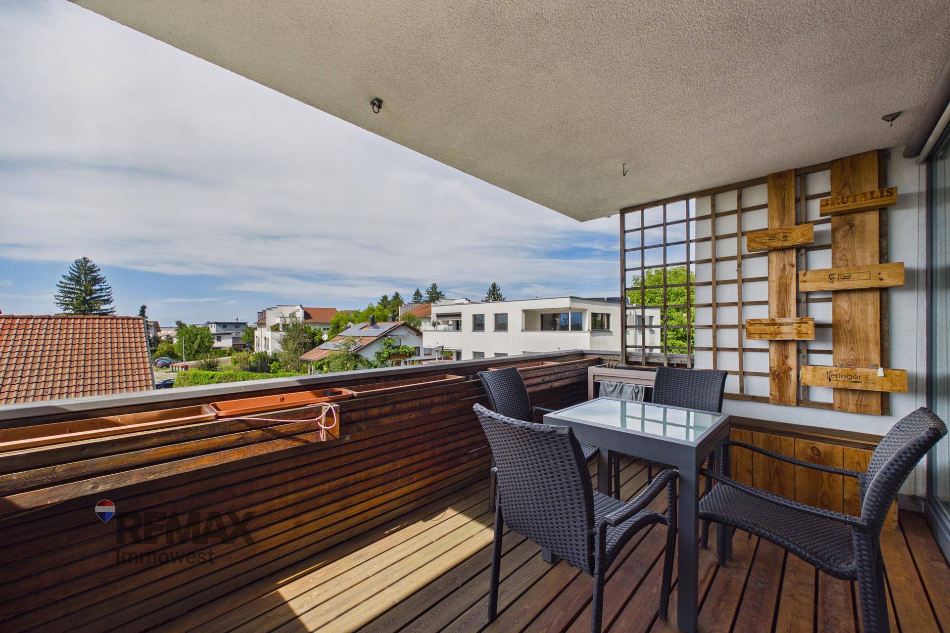 Geräumiger Balkon mit Holzboden und Sitzgelegenheiten, bietet einen angenehmen Ausblick.