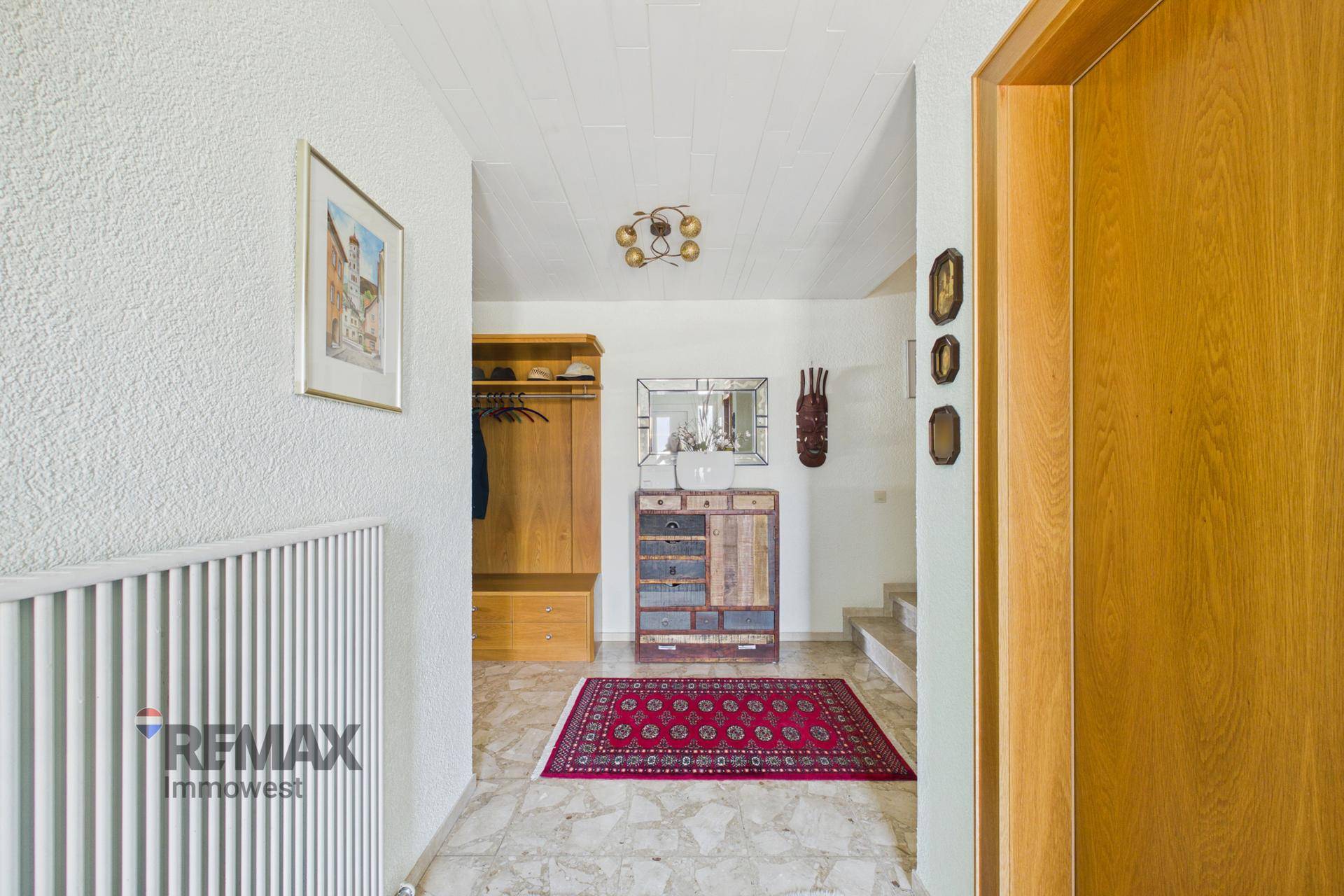 Heller Eingangsbereich mit Marmorboden, Garderobe und dekorativen Elementen.