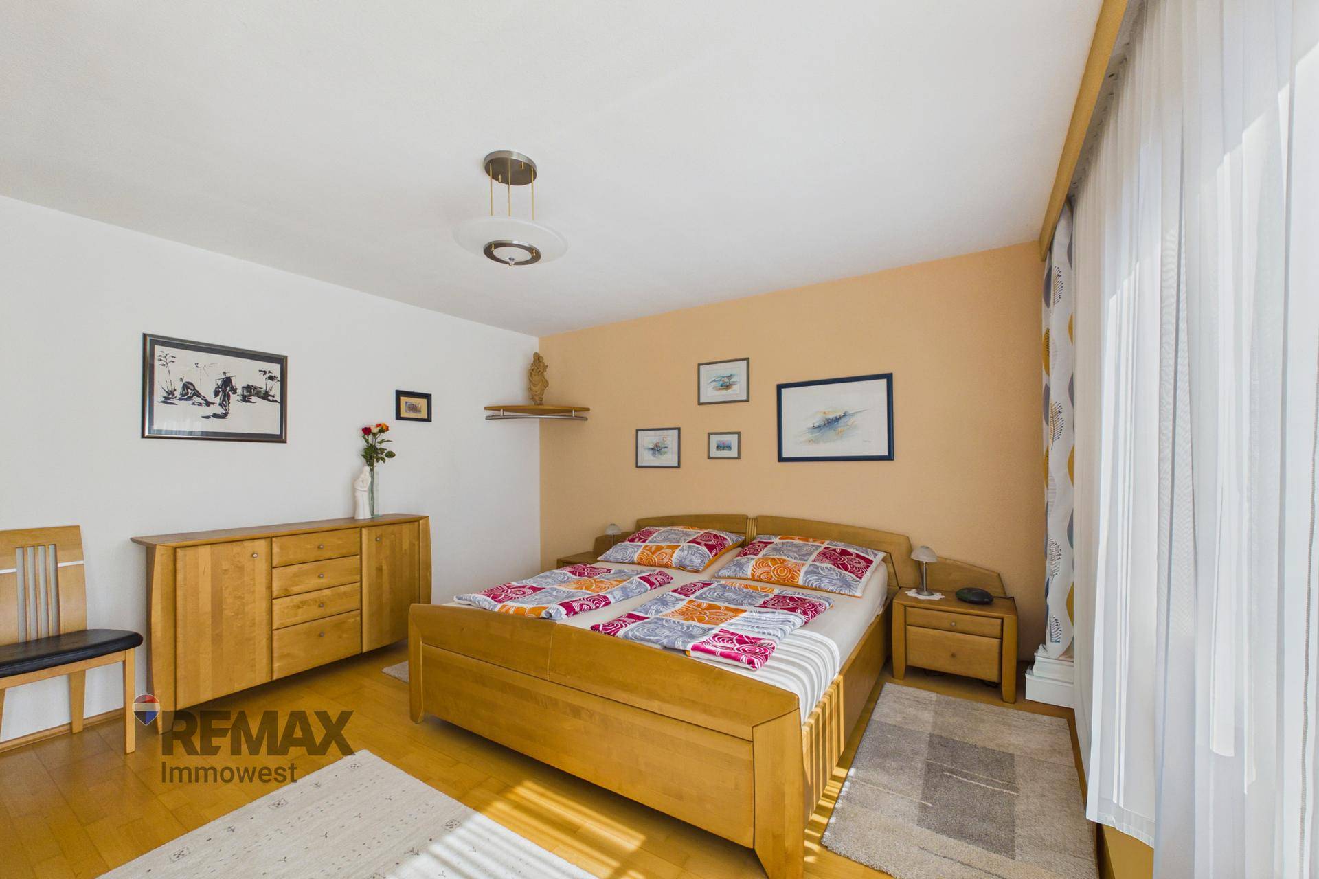 Helles Schlafzimmer mit Holzmöbeln, Parkettboden und viel Tageslicht.