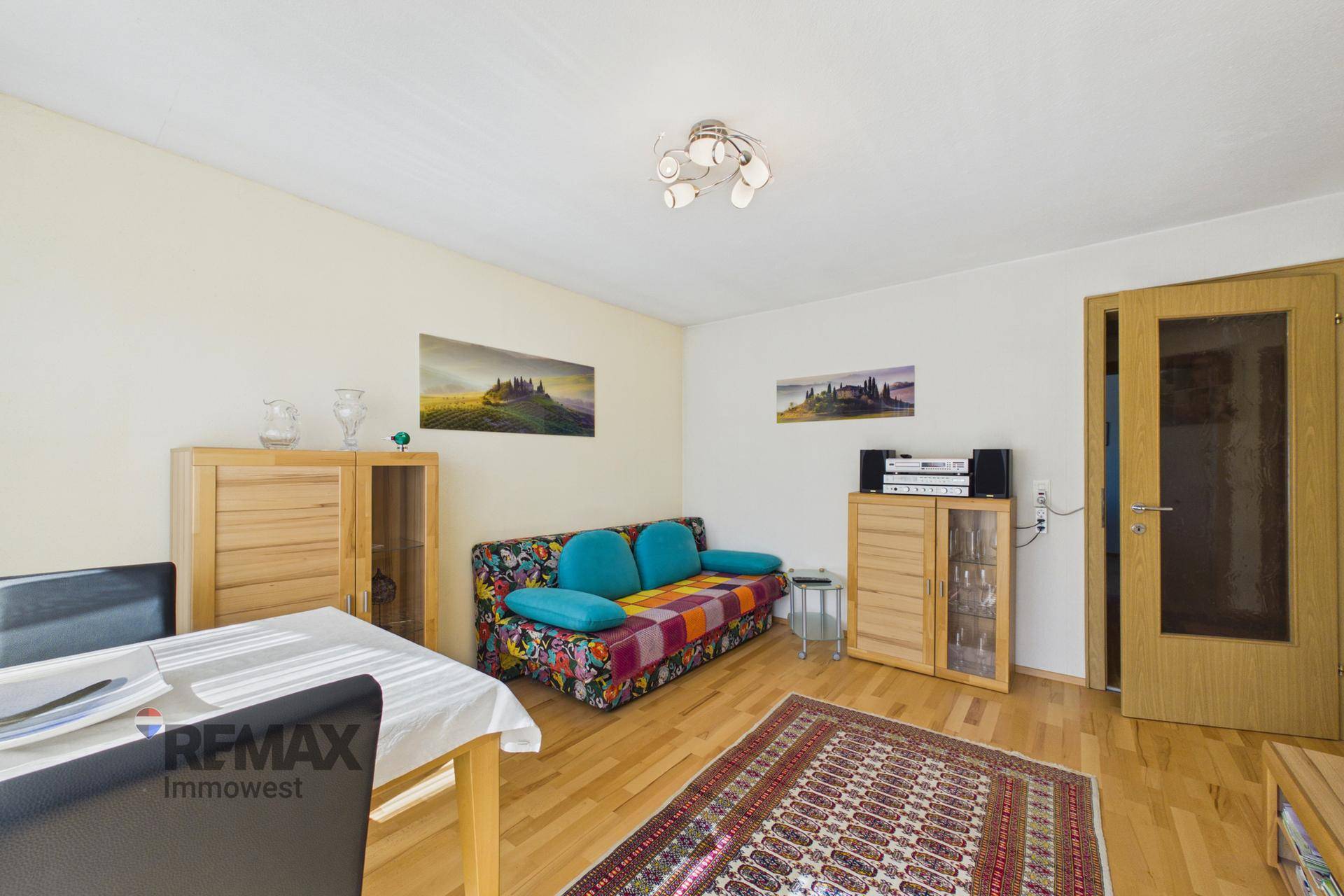 Helles Zimmer mit Schlafsofa, Esstisch und Parkettboden.
