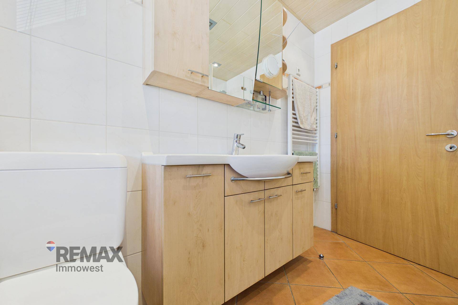 Modernes Badezimmer mit Waschbeckenunterschrank, WC und Terrakottafliesen.