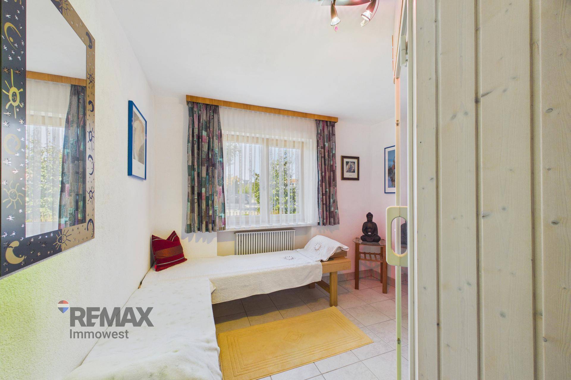Helles Gästezimmer mit Einzelbett, Fliesenboden und Fensterblick.