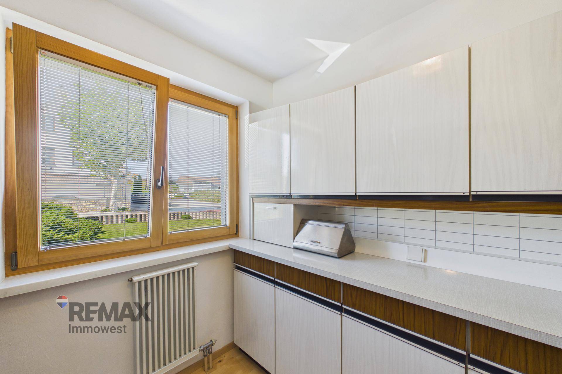 Praktischer Hauswirtschaftsraum mit Arbeitsfläche, Schränken und Fenster.