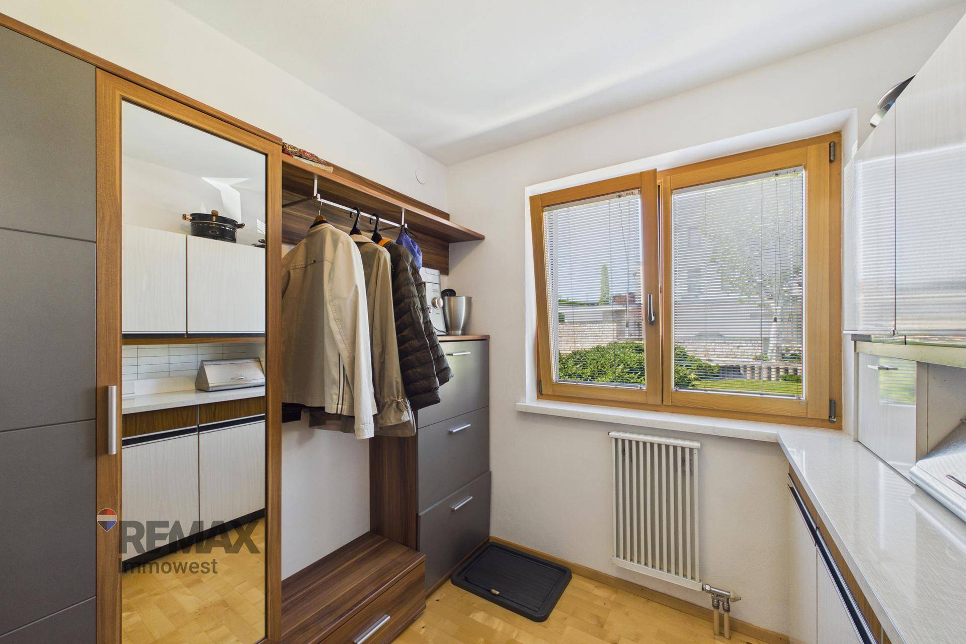 Funktionaler Raum mit Garderobe, Spiegel und Fenster.