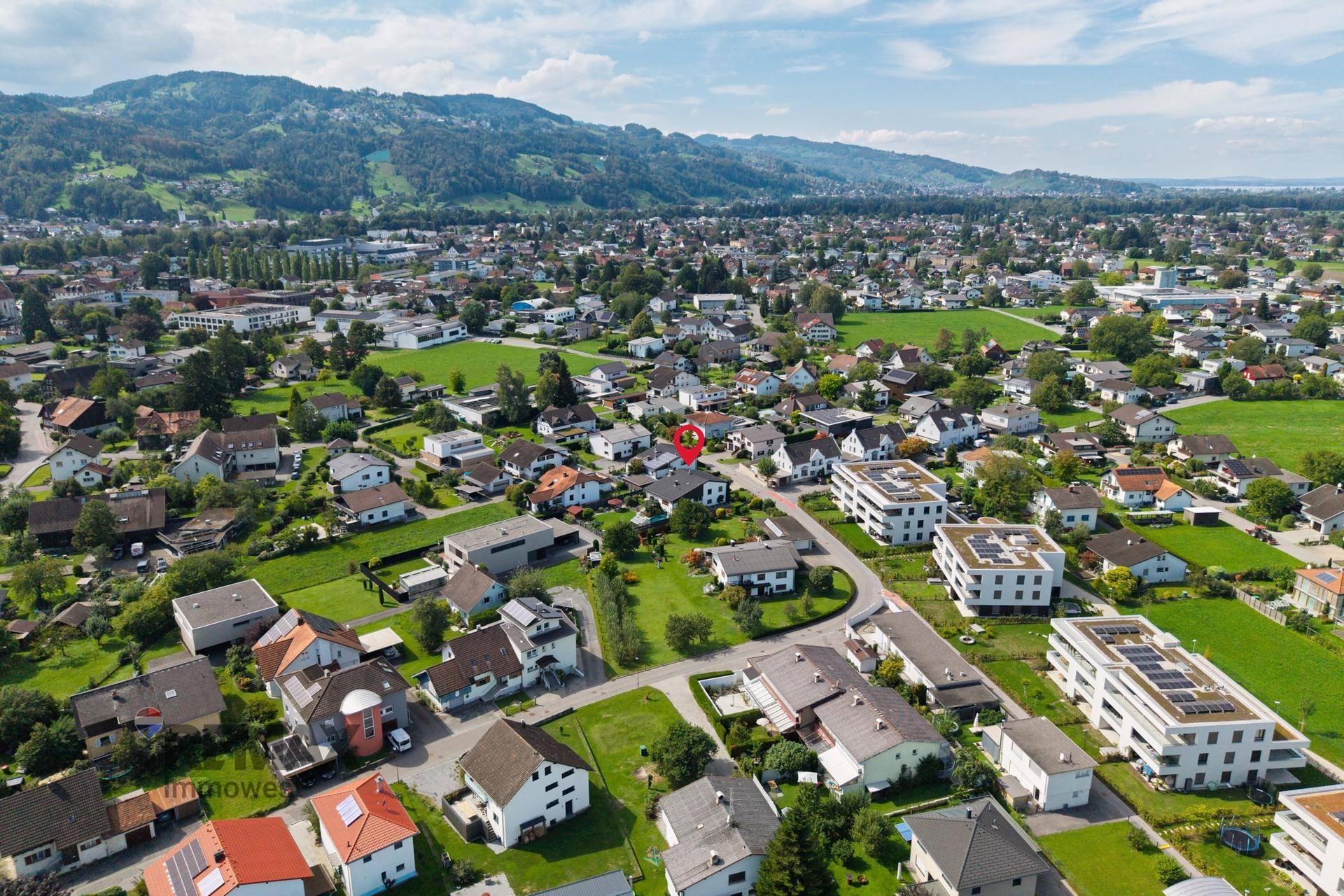 Panoramablick aus der Luft auf die Wohngegend mit Bergen und See im Hintergrund an einem klaren Tag.