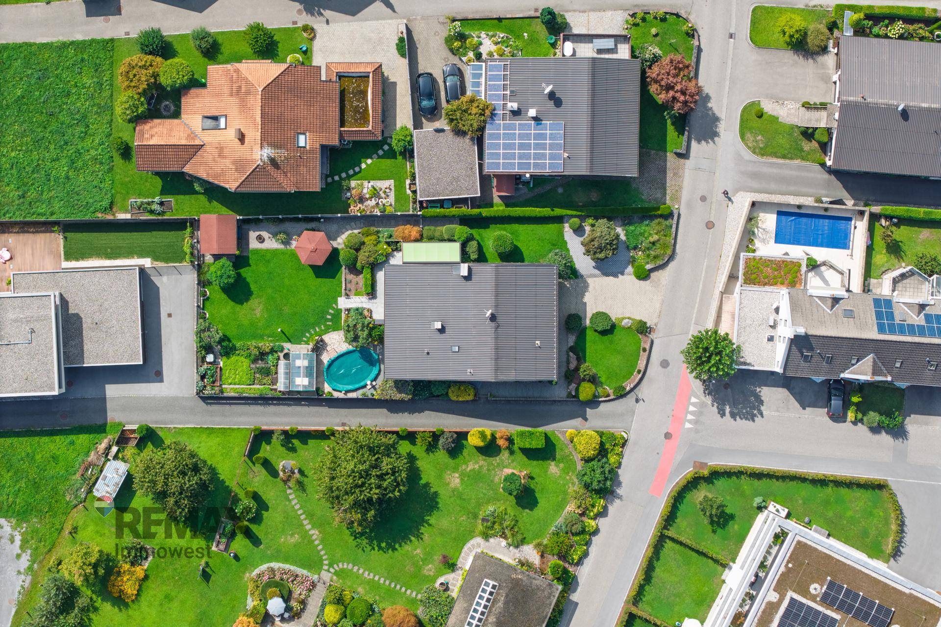Luftaufnahme des Grundstücks mit Haus, Garten, Pool und umliegender Bebauung in einer Wohngegend.