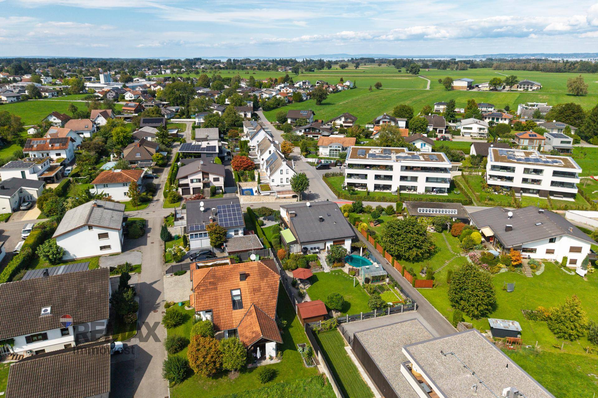 Weitläufige Luftaufnahme der Wohnsiedlung mit Einfamilienhäusern und grünen Feldern in der Ferne.